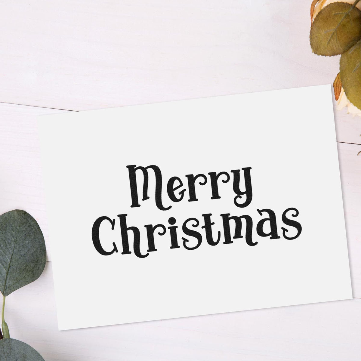 Black Merry Christmas stamp on white card with eucalyptus leaves, for custom stamp and seal products.