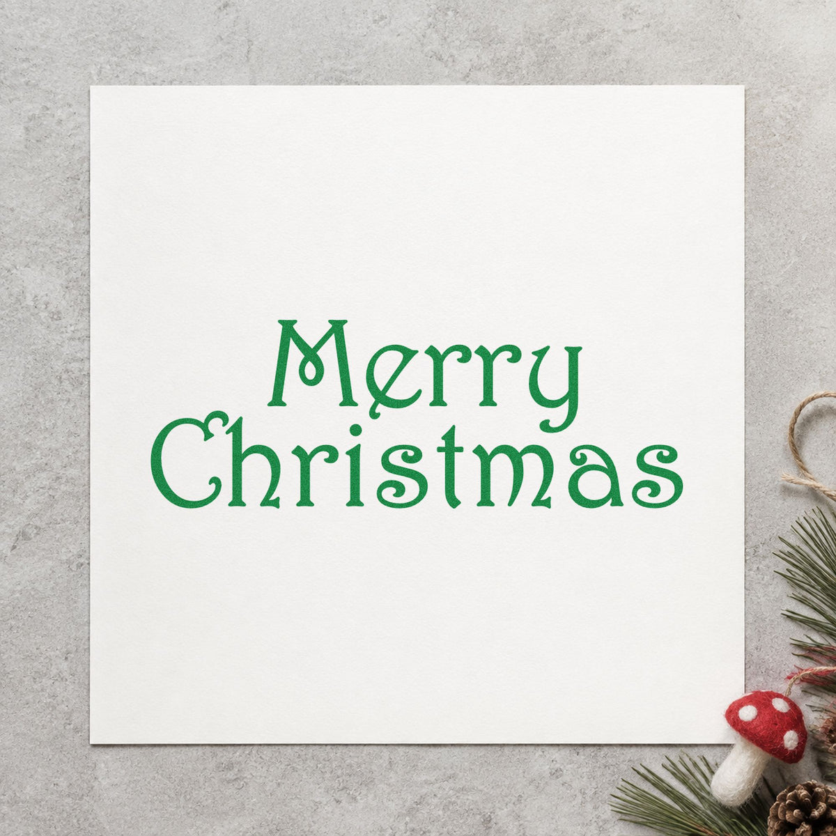 Merry Christmas Thin Serif craft stamp imprint in green ink on a handmade project, one idea being tissue thin tags.