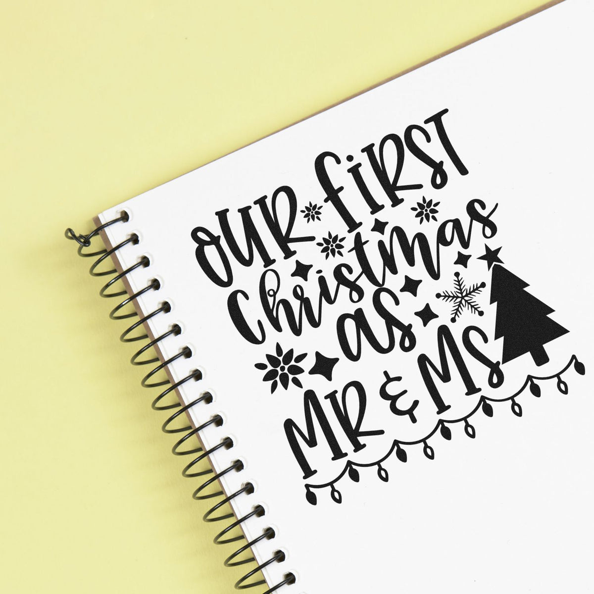 Black Christmas stamp and seal design reading Our First Christmas as Mr & Mrs with snowflakes and tree on pale yellow.