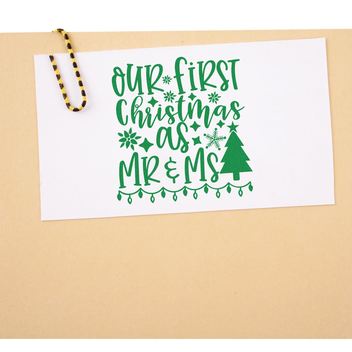 Green Christmas stamp and seal design on white card: Our First Christmas as Mr & Ms with tree, stars, and paperclip.