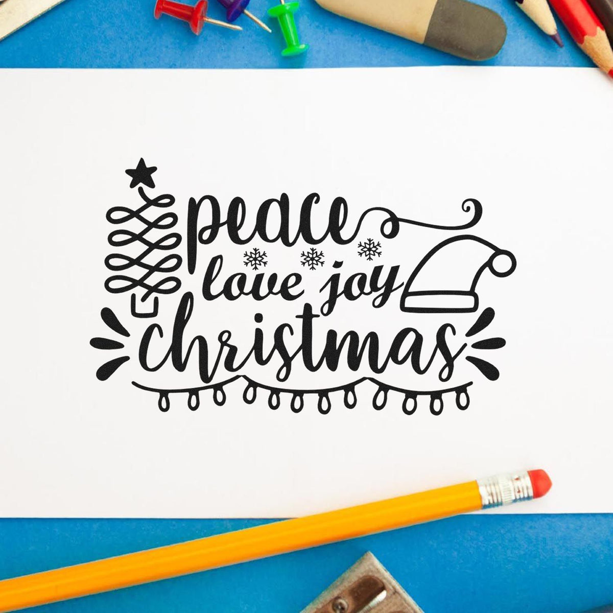 Black Christmas stamp and seal design on white paper, with peace love joy, Santa hat, snowflakes and string lights on blue background.