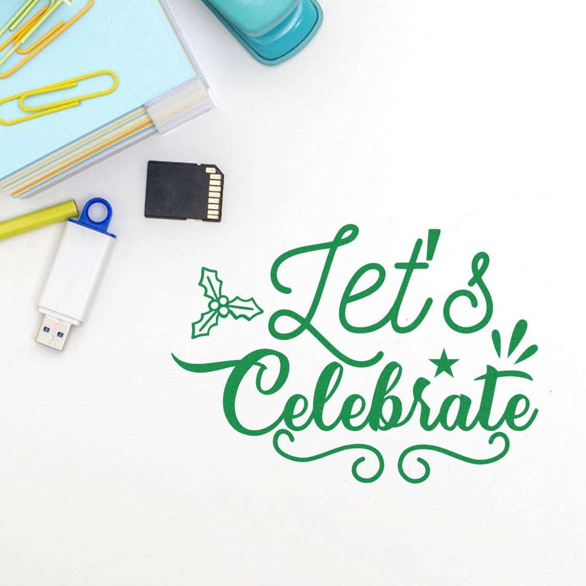 Green Lets Celebrate stamp and seal design with holly, star, and confetti on white, plus paper clips and USB drive
