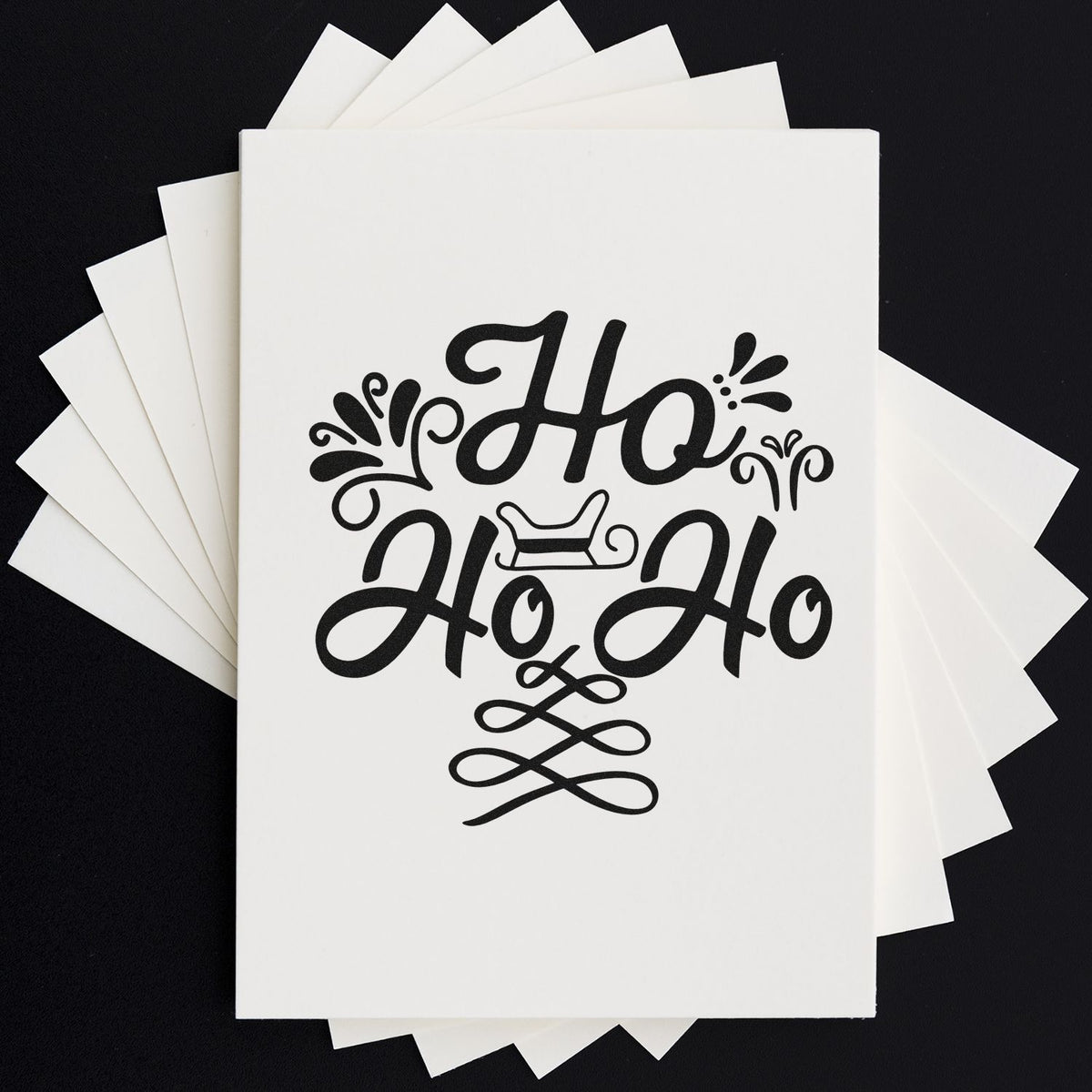 White stamp and seal cards with black decorative Ho Ho Ho holiday design on a black background.