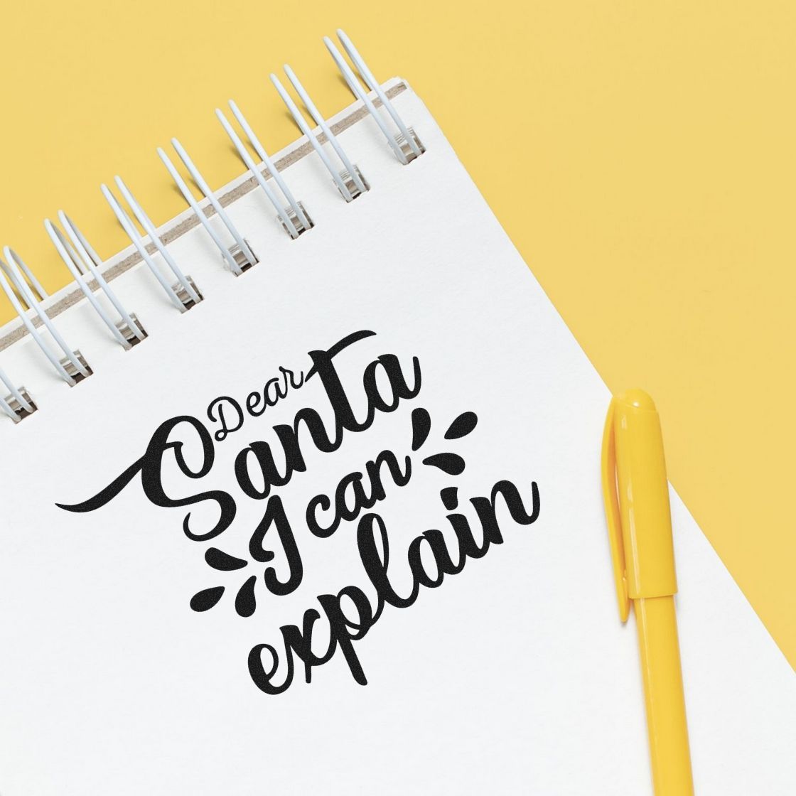 Custom stamp-style notebook design reading Dear Santa, I can explain with a yellow pen on a pale yellow background.