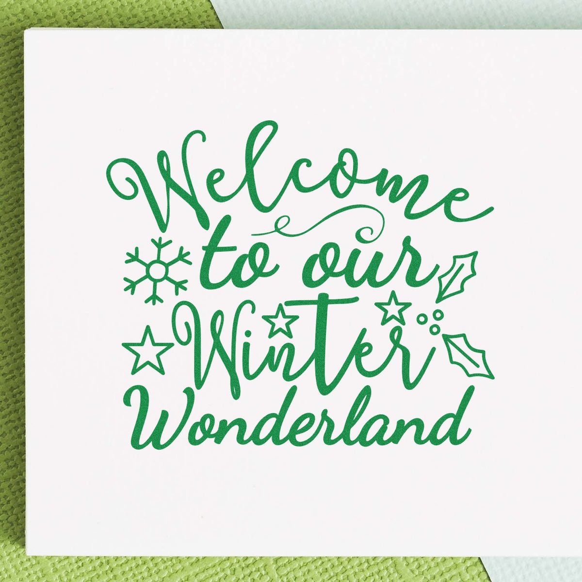 Green winter welcome stamp/seal design on white card, with script lettering, snowflake, stars, and holly accents.