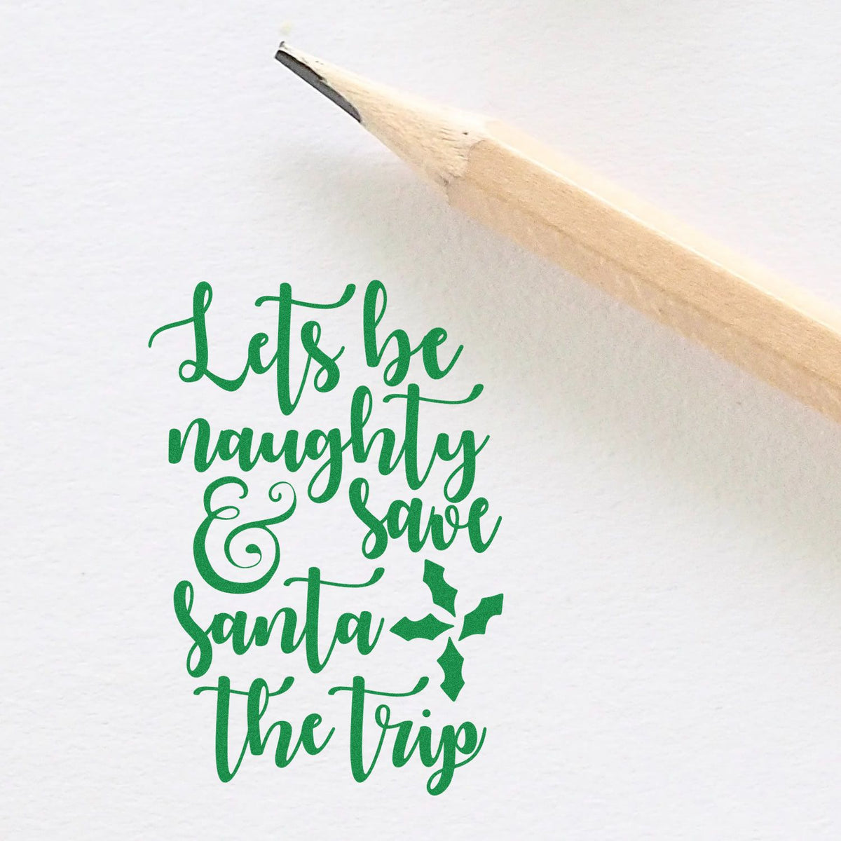 Green holiday stamp/seal design reading Lets be naughty & save Santa the trip with holly and a pencil tip.
