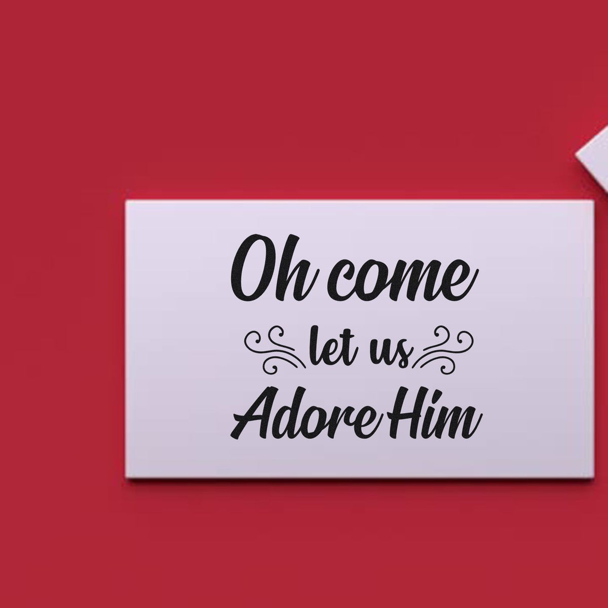 White stamp-and-seal card with black script reading Oh come let us Adore Him on a red background.