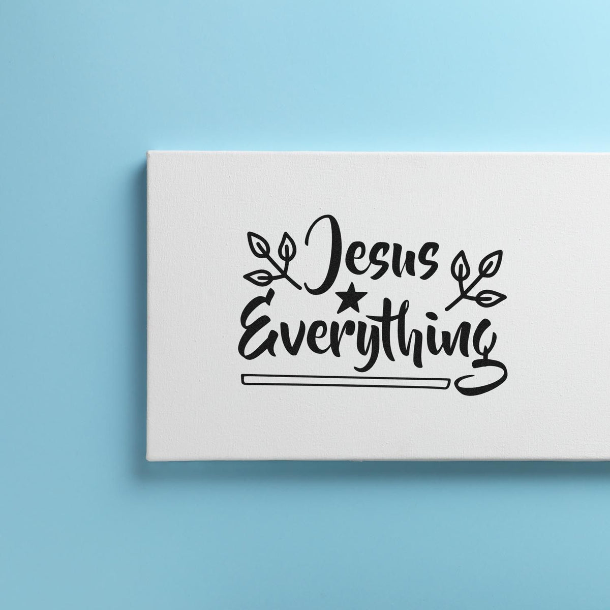 Black Jesus Everything stamp/seal design on a white rectangular block, with leaf accents and star, against a light blue background.