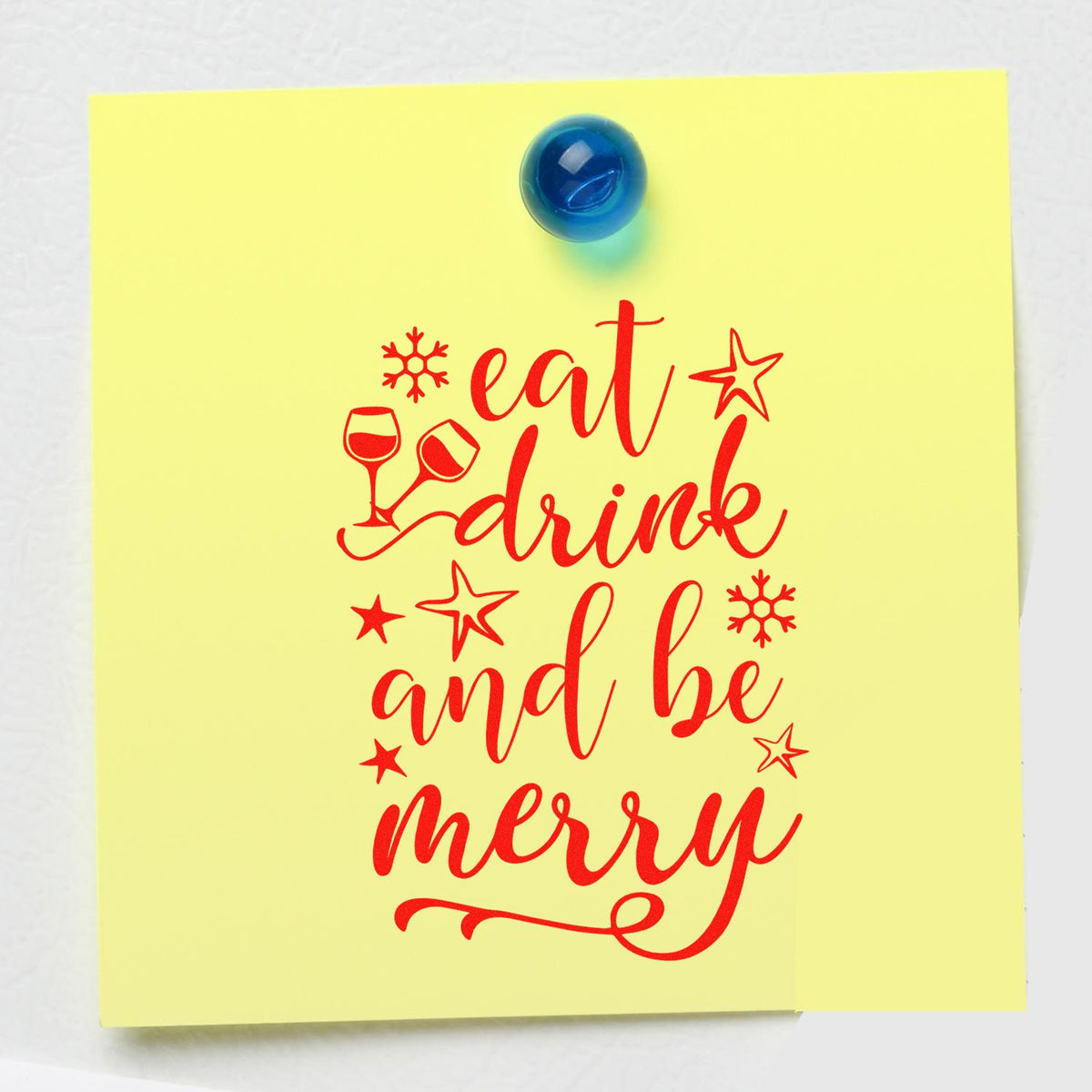Yellow card with red holiday stamp design reading eat, drink and be merry, plus wine glasses, stars, and snowflakes.