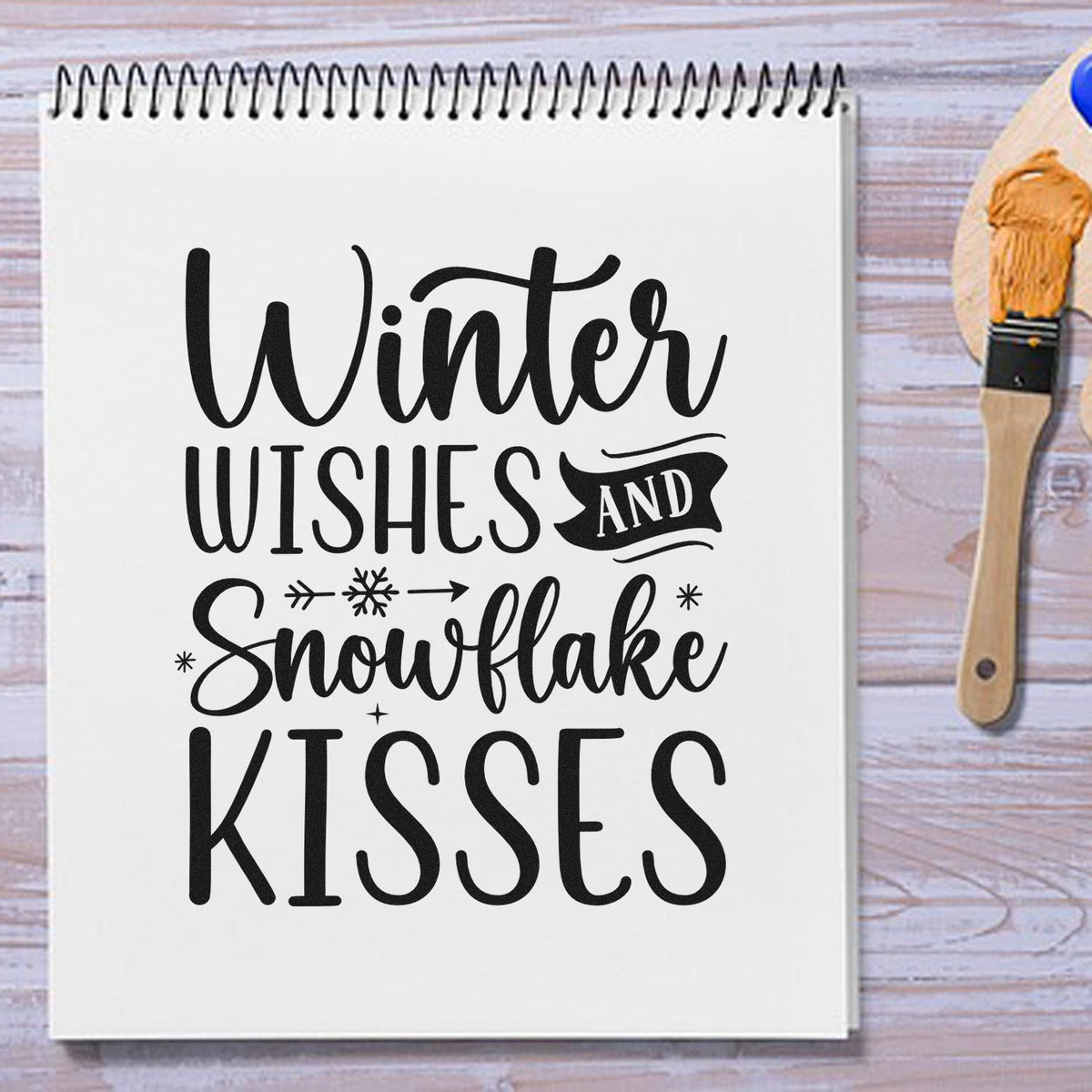 Black winter stamp on white notebook with Winter Wishes and Snowflake Kisses; orange seal brush tool at right.