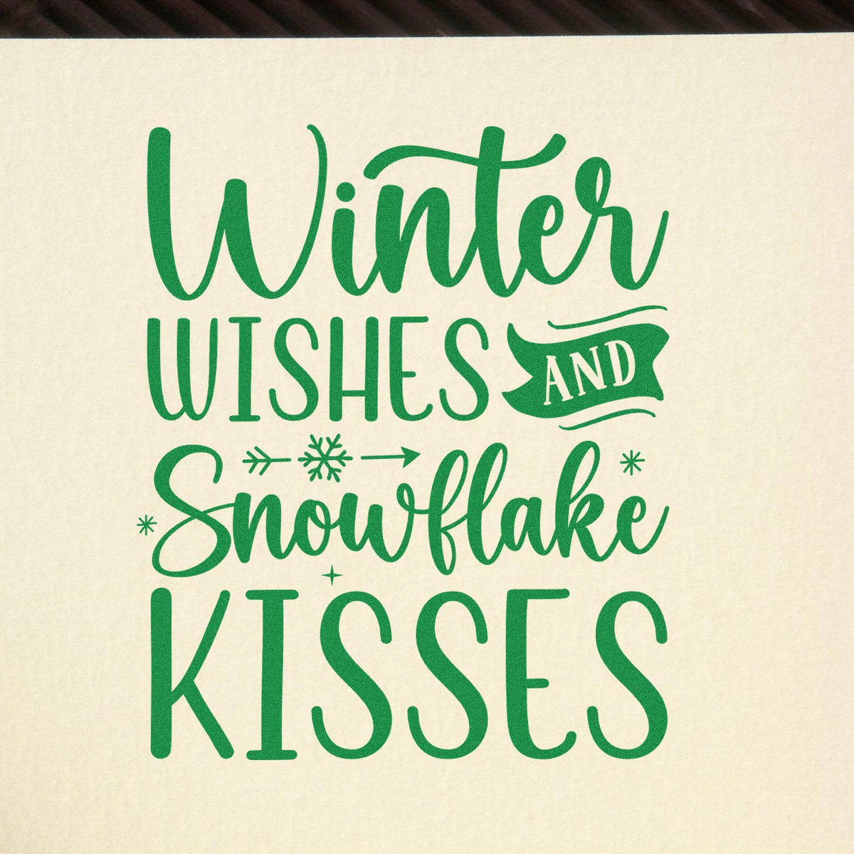 Green winter greeting stamp seal on cream background with Winter Wishes and Snowflake Kisses and snowflake accents.