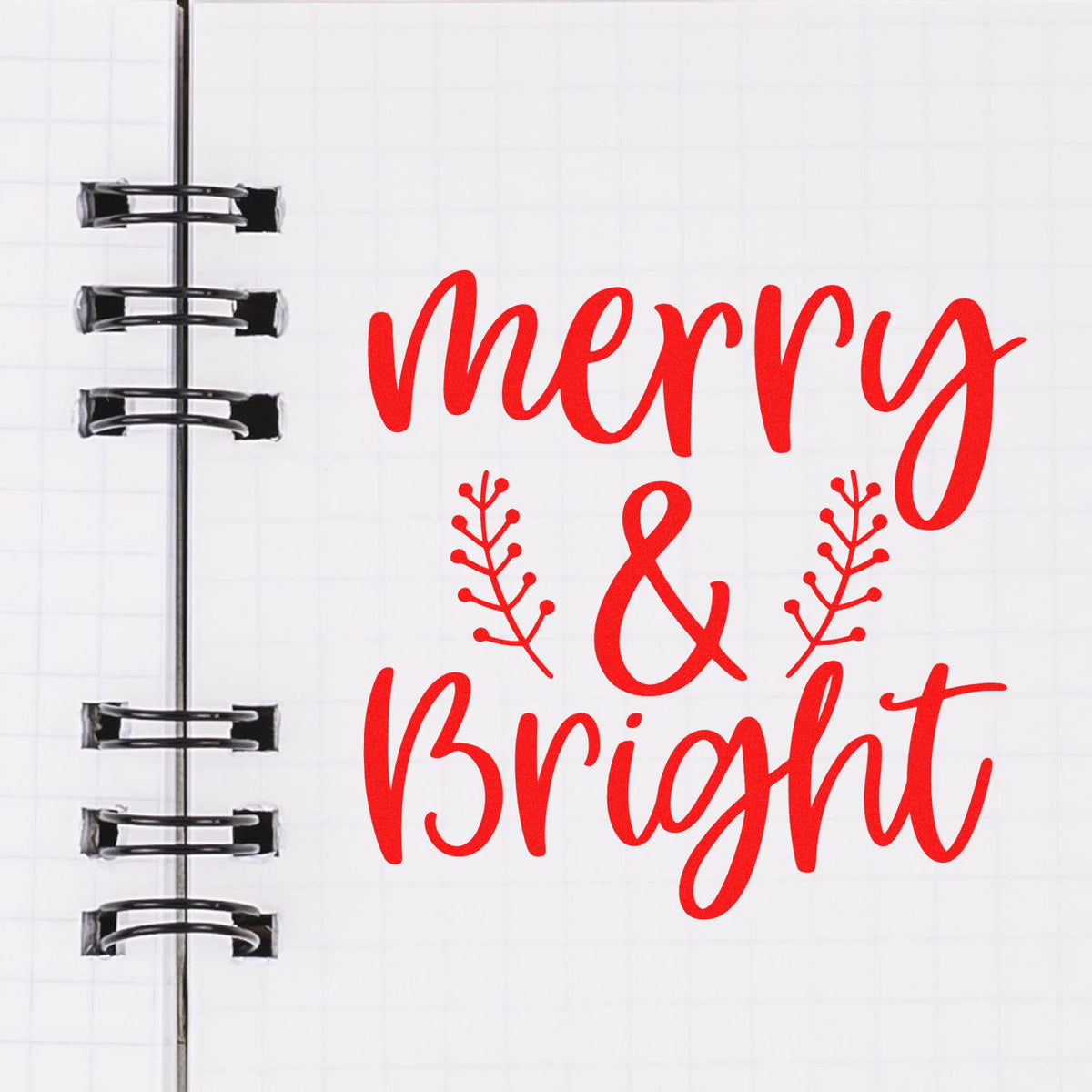 Red Merry & Bright stamp and seal design with decorative leaves on white notebook page and black binder rings.
