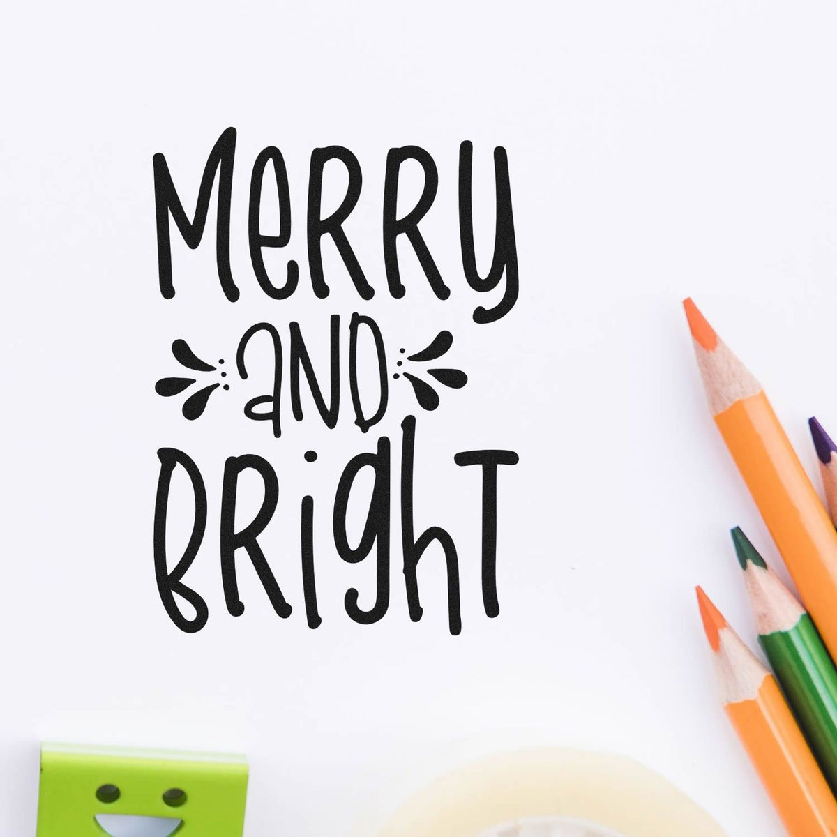 Merry and Bright black stamp on white paper with orange, green and purple pencils and a partial green seal at bottom left.