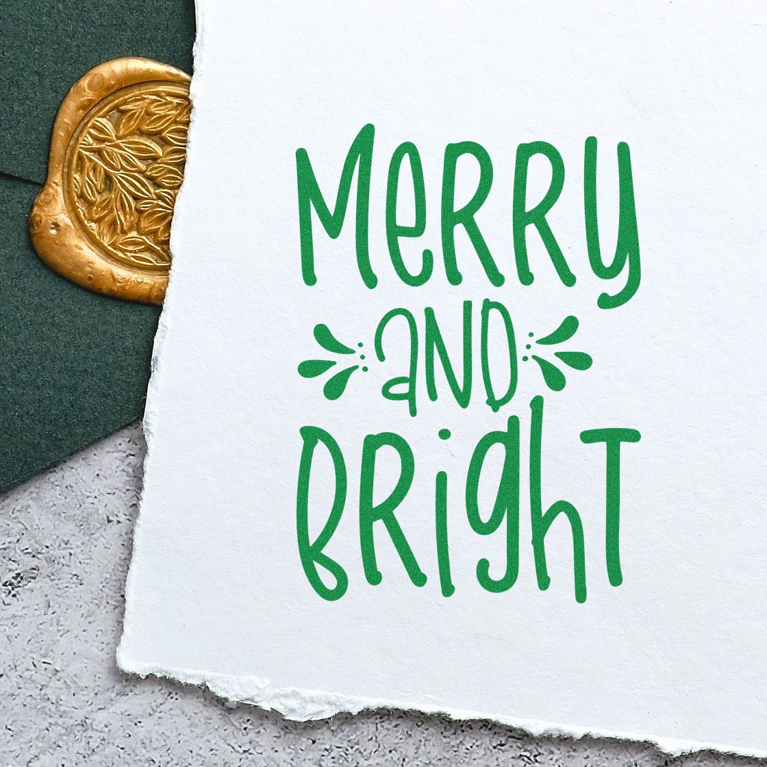 Green Merry and Bright holiday stamp on white paper, with a gold embossed wax seal peeking from the left.