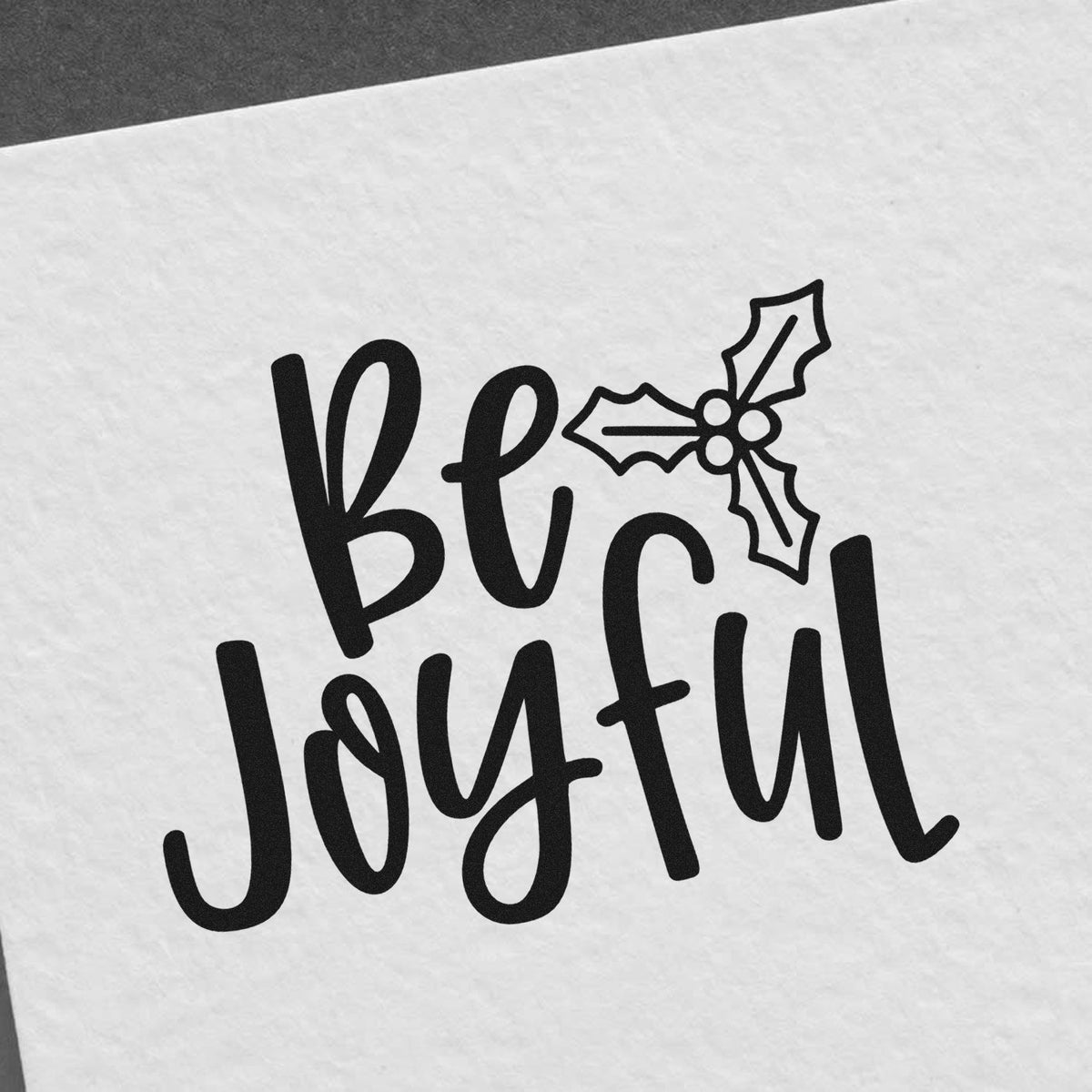 Black be joyful holiday stamp and seal design with holly icon on white paper.