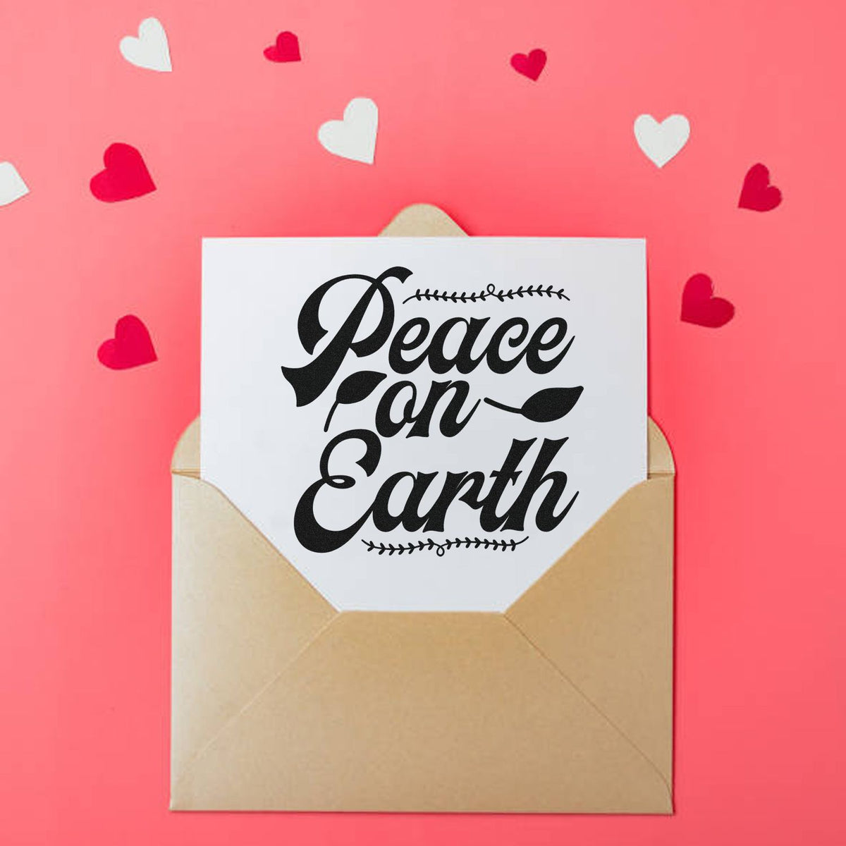 Heart-themed stamp seal on white card in a brown envelope, with black Peace on Earth lettering on a pink background.