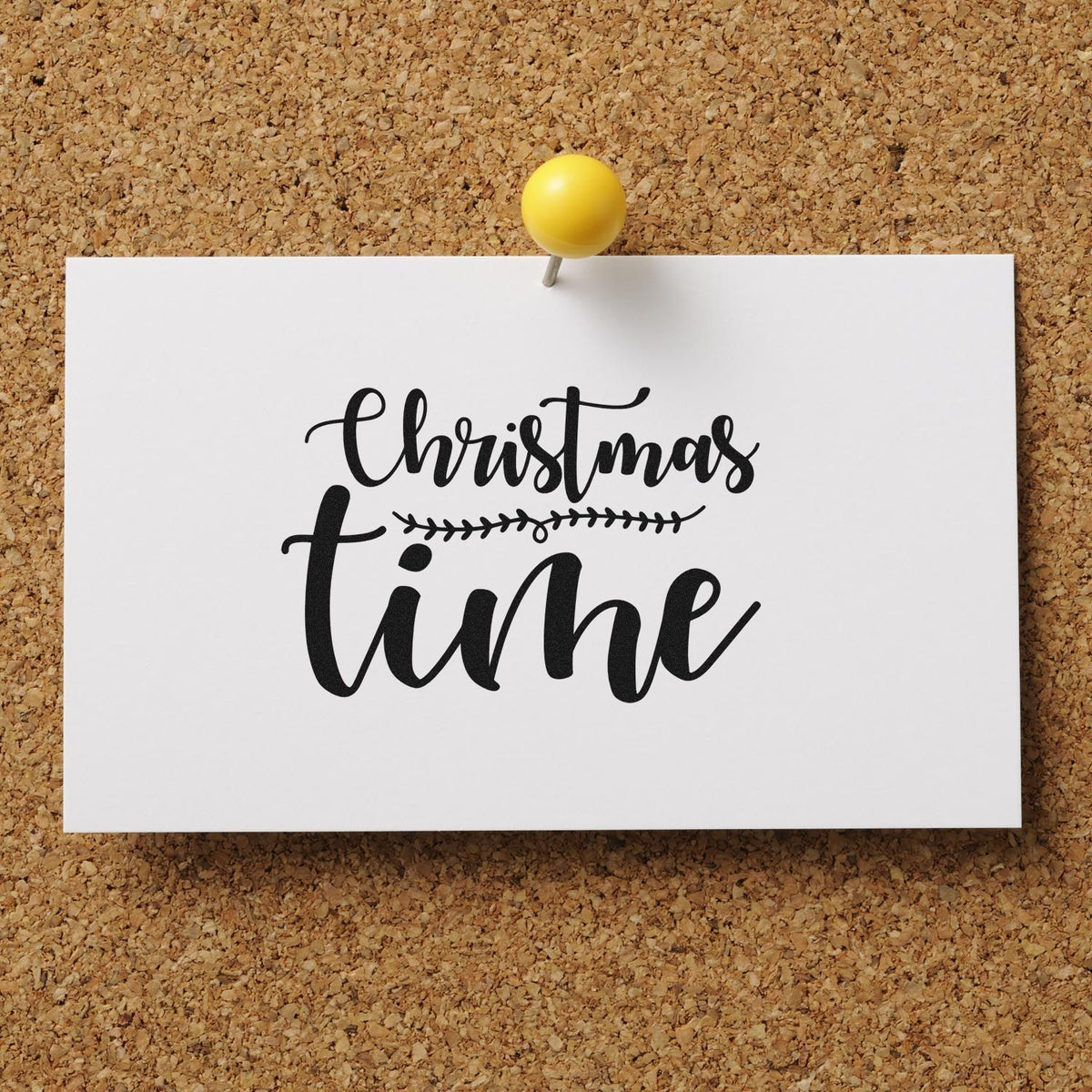 White card with black Christmas time stamp design, pinned by a yellow pushpin on a corkboard.