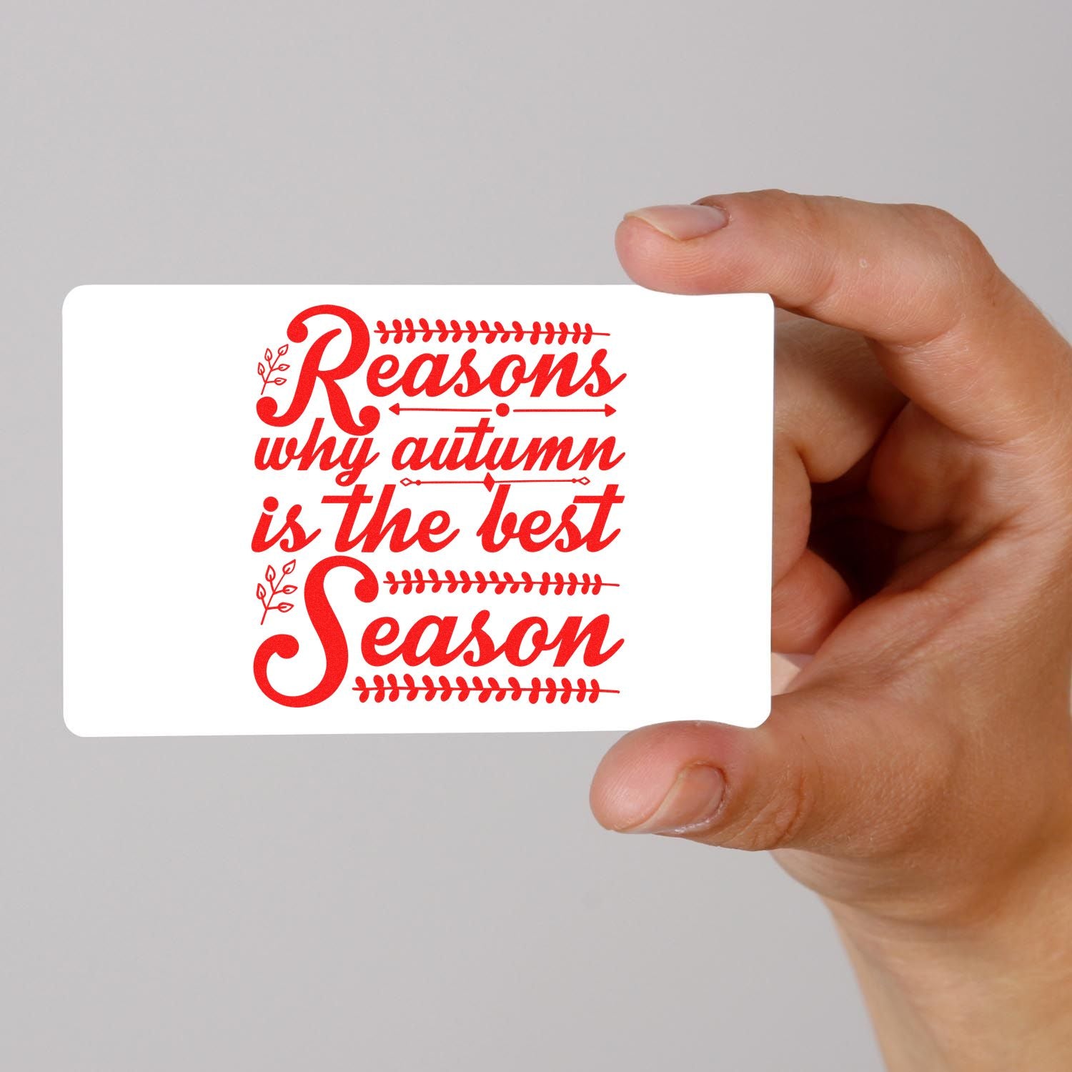 Hand holding a white stamp card with a red autumn-themed seal reading Reasons why autumn is the best season