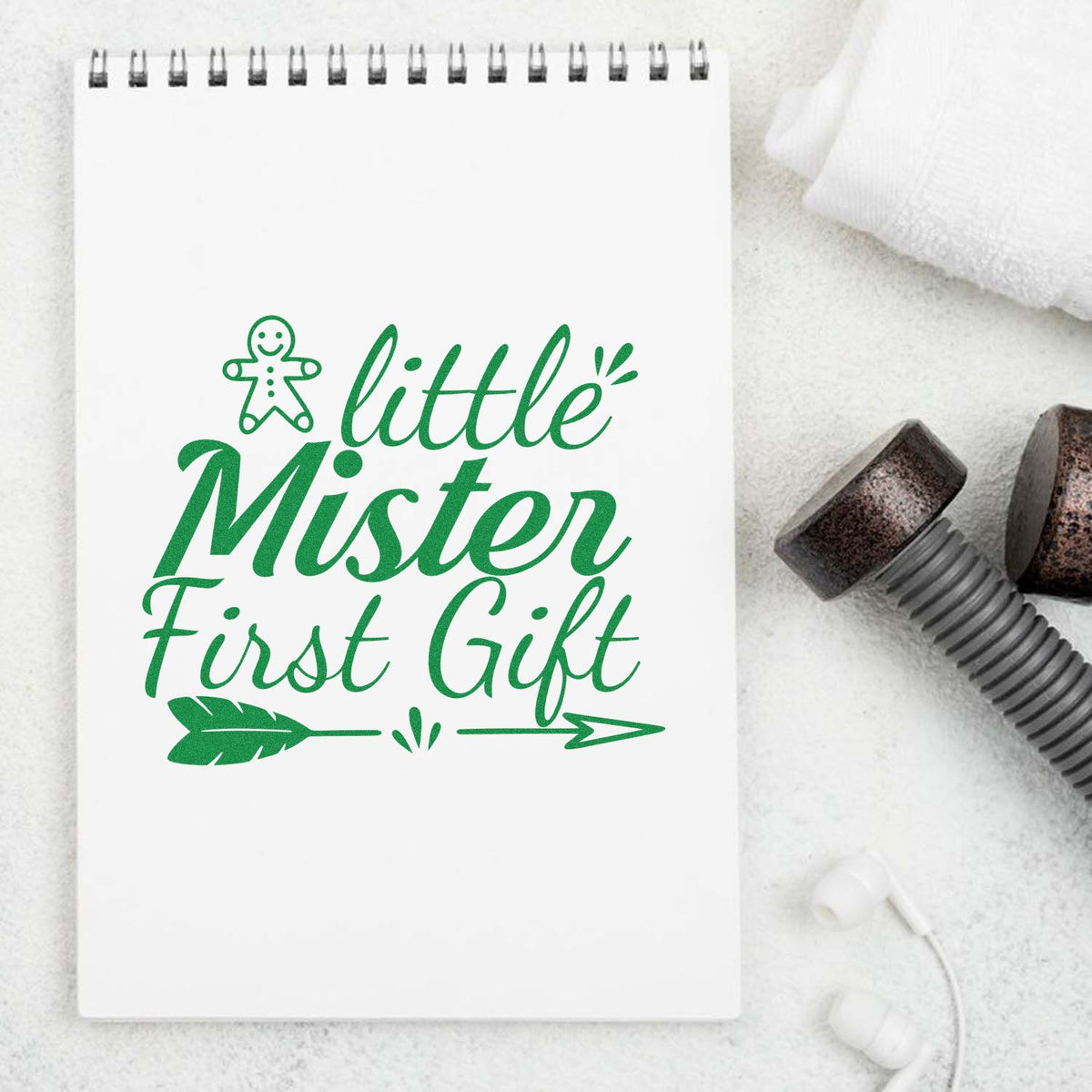 Green Little Mister First Gift stamp seal on white spiral notebook, with gingerbread icon and arrow accents.