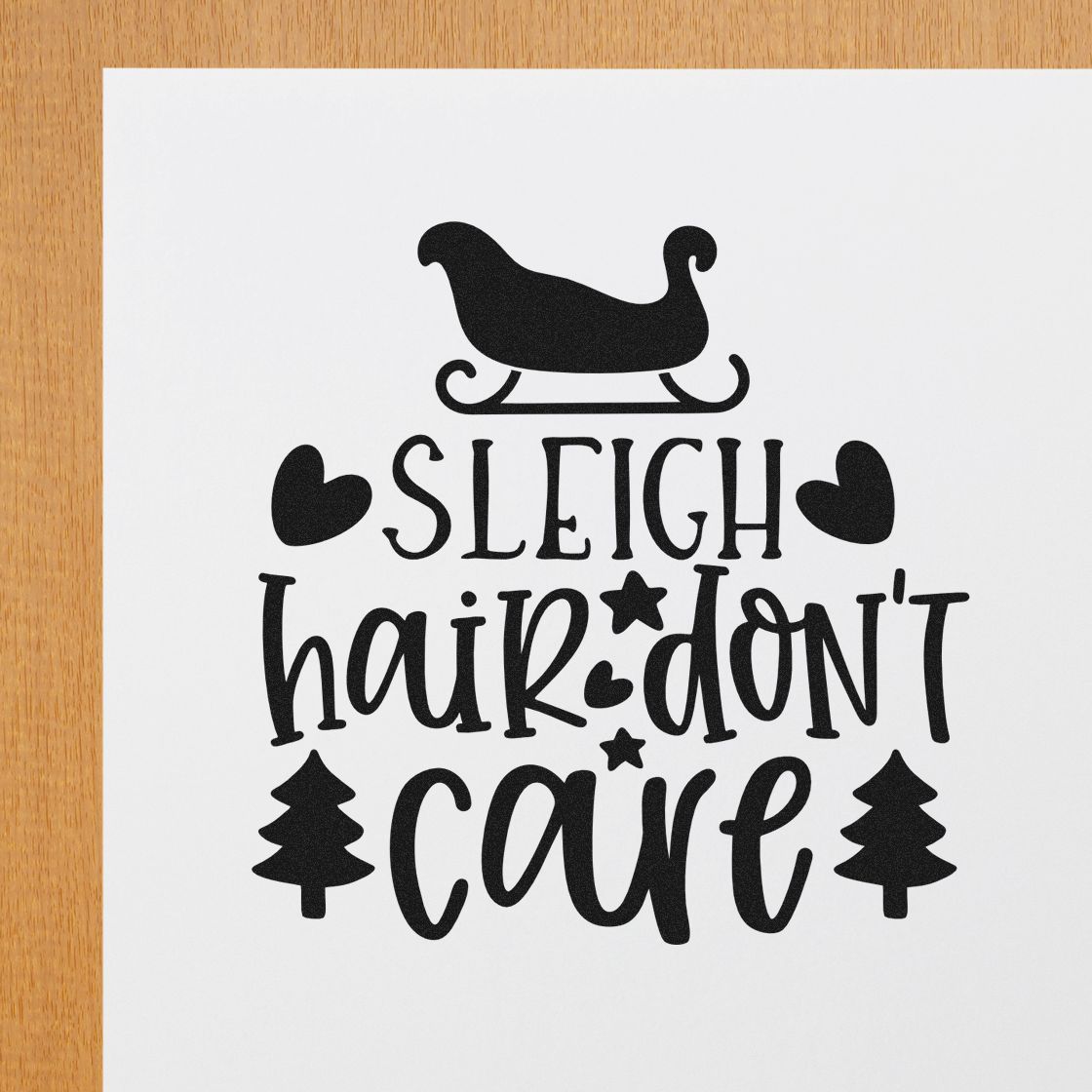 Black holiday stamp and seal design with sleigh silhouette, Sleigh Hair Dont Care text, hearts, stars, and pine trees on white.