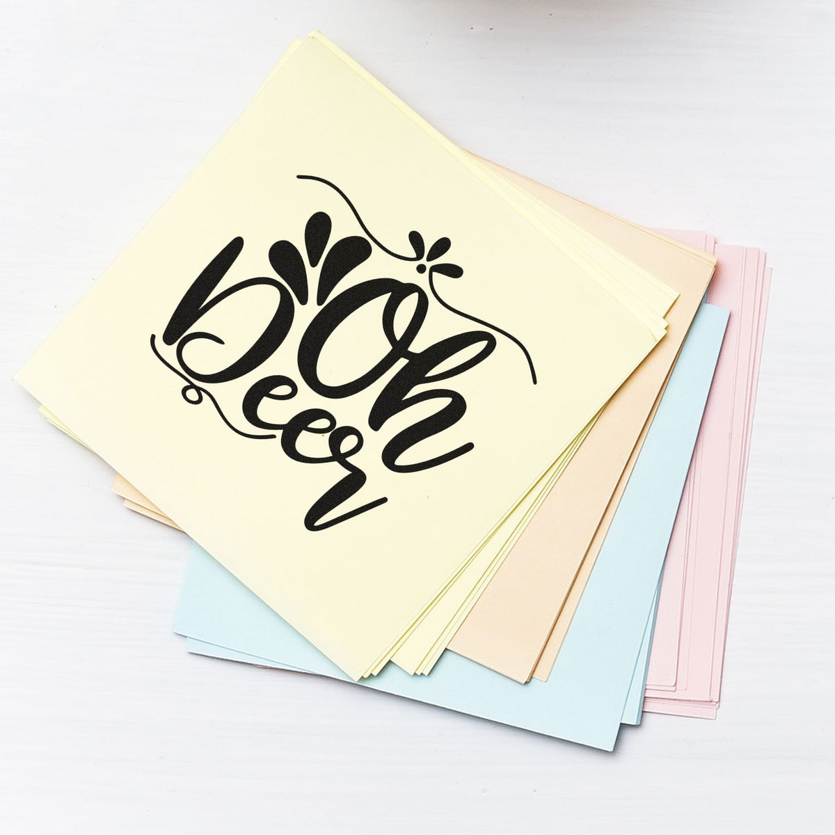 Pastel stamp and seal paper samples with black decorative script on cream, blue, pink and beige sheets.