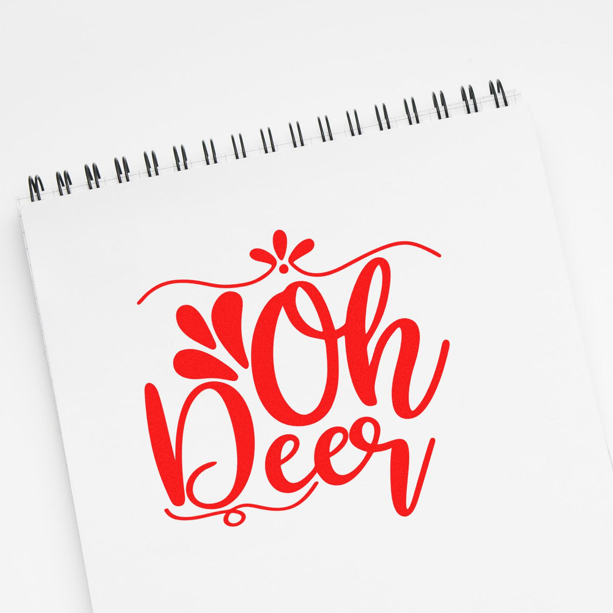White spiral notebook with a red Oh Deer decorative stamp and seal design