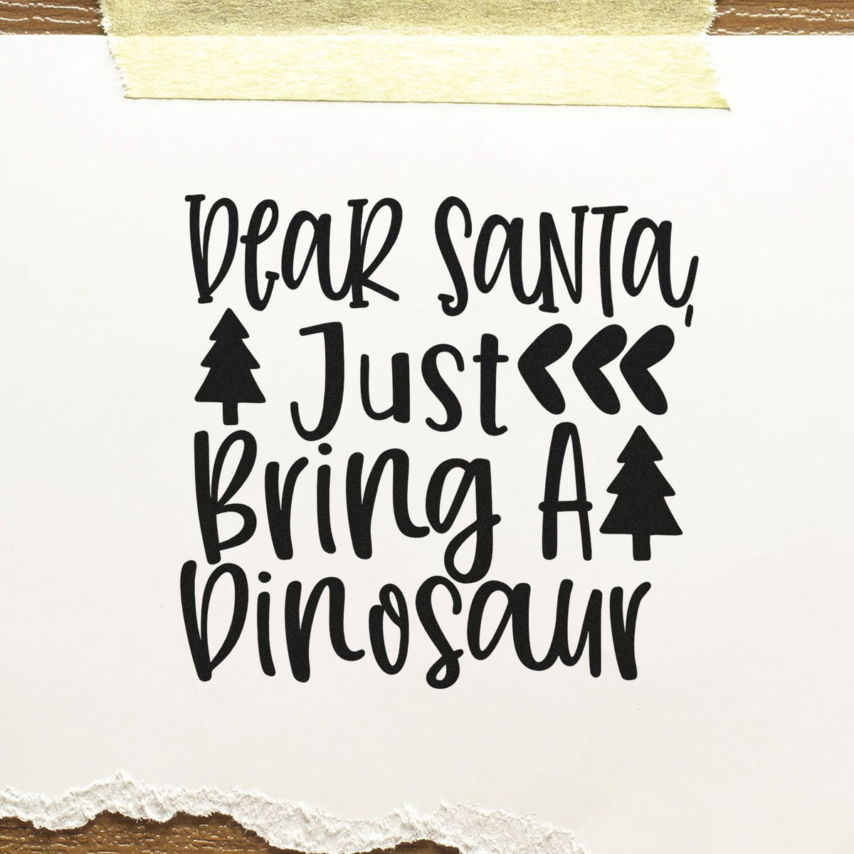 Black holiday stamp reading Dear Santa, Just Bring a Dinosaur with tree icons on white paper.