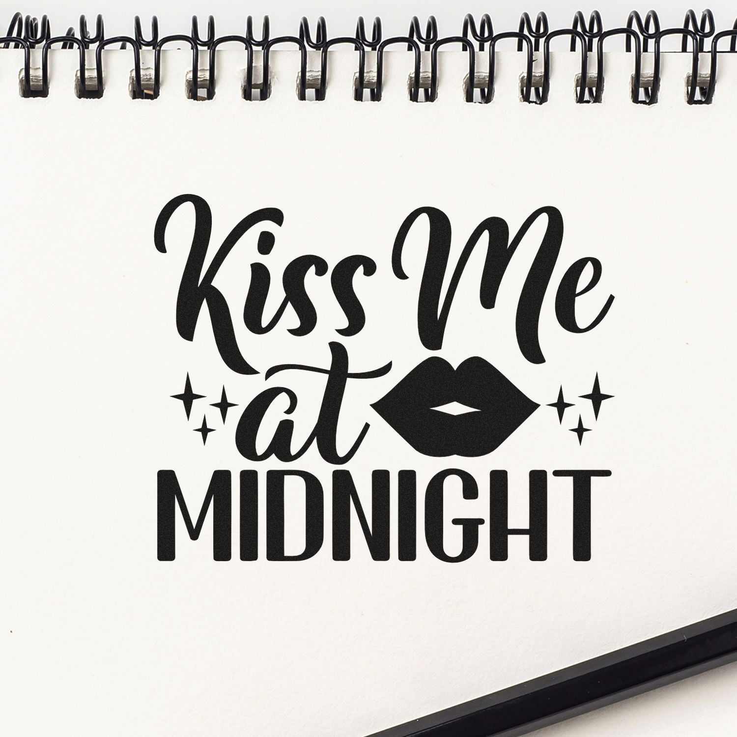 Black Kiss Me at Midnight stamp design with lips and sparkles on a white spiral-bound notebook page.