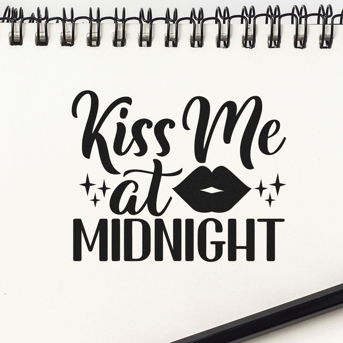 Black Kiss Me at Midnight stamp and seal design with lips and sparkles on a white spiral-bound page.