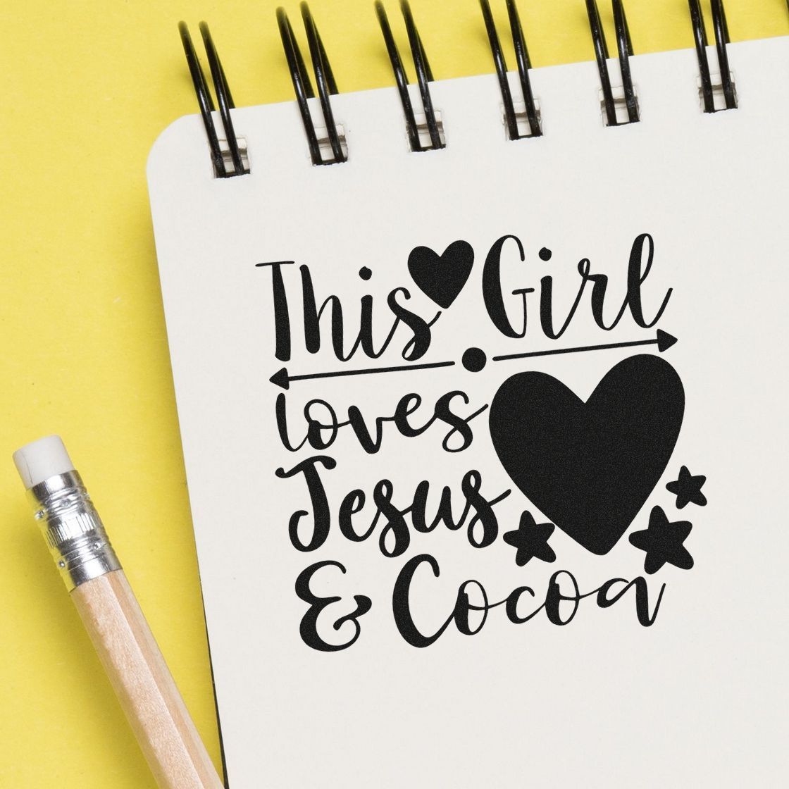 Black custom stamp design on white spiral notebook reads This Girl loves Jesus & Cocoa with heart and stars on yellow background.