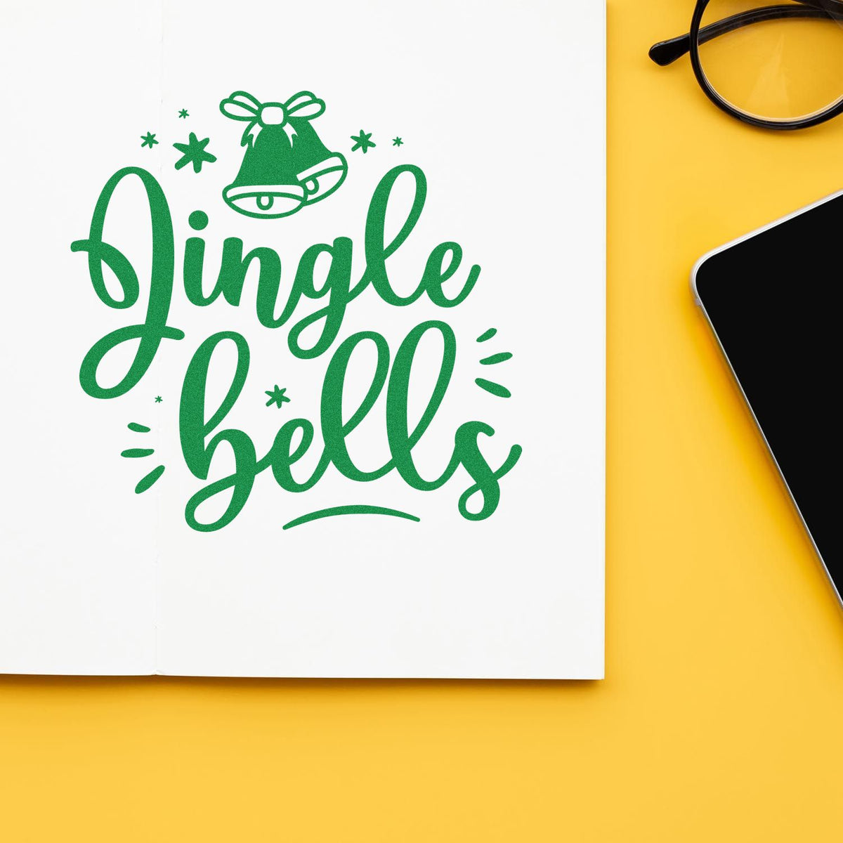 Green Jingle Bells stamp seal with bell icon on white paper, set against a bright yellow background.