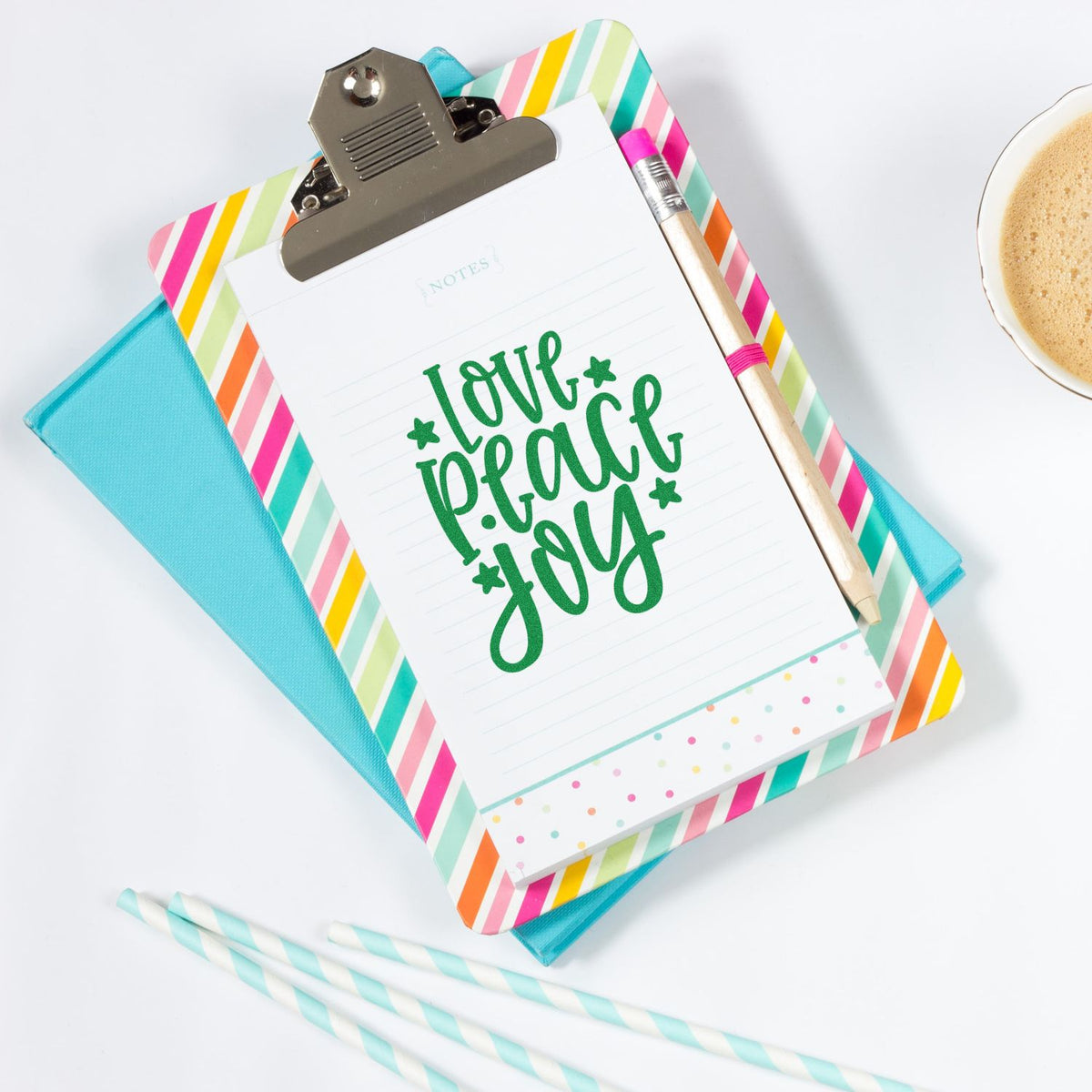 Colorful stamp and seal stationery set with striped clipboard, green love peace joy notepad, pencil, and turquoise folder.