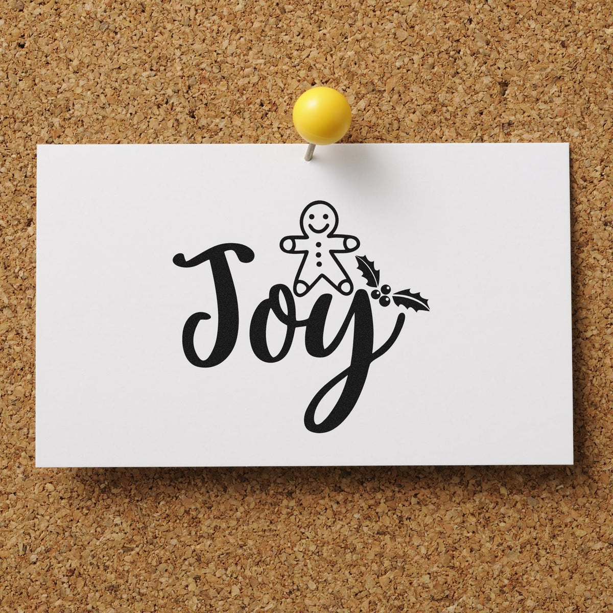 Black Joy holiday stamp and seal on white card, with gingerbread figure, holly, and yellow pushpin on cork board.
