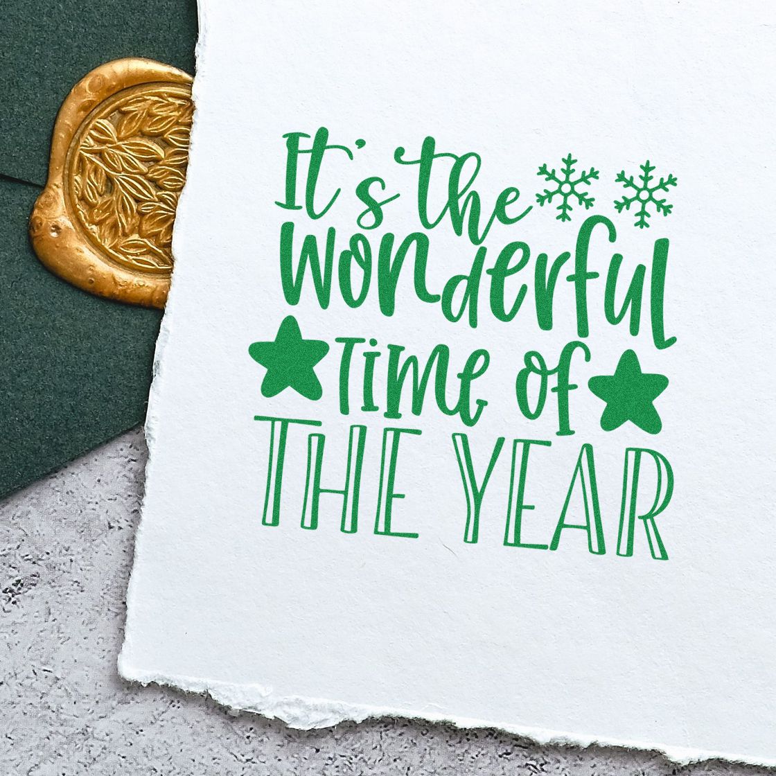 Green stamped holiday greeting on white paper, with gold embossed seal and snowflakes on dark green background.