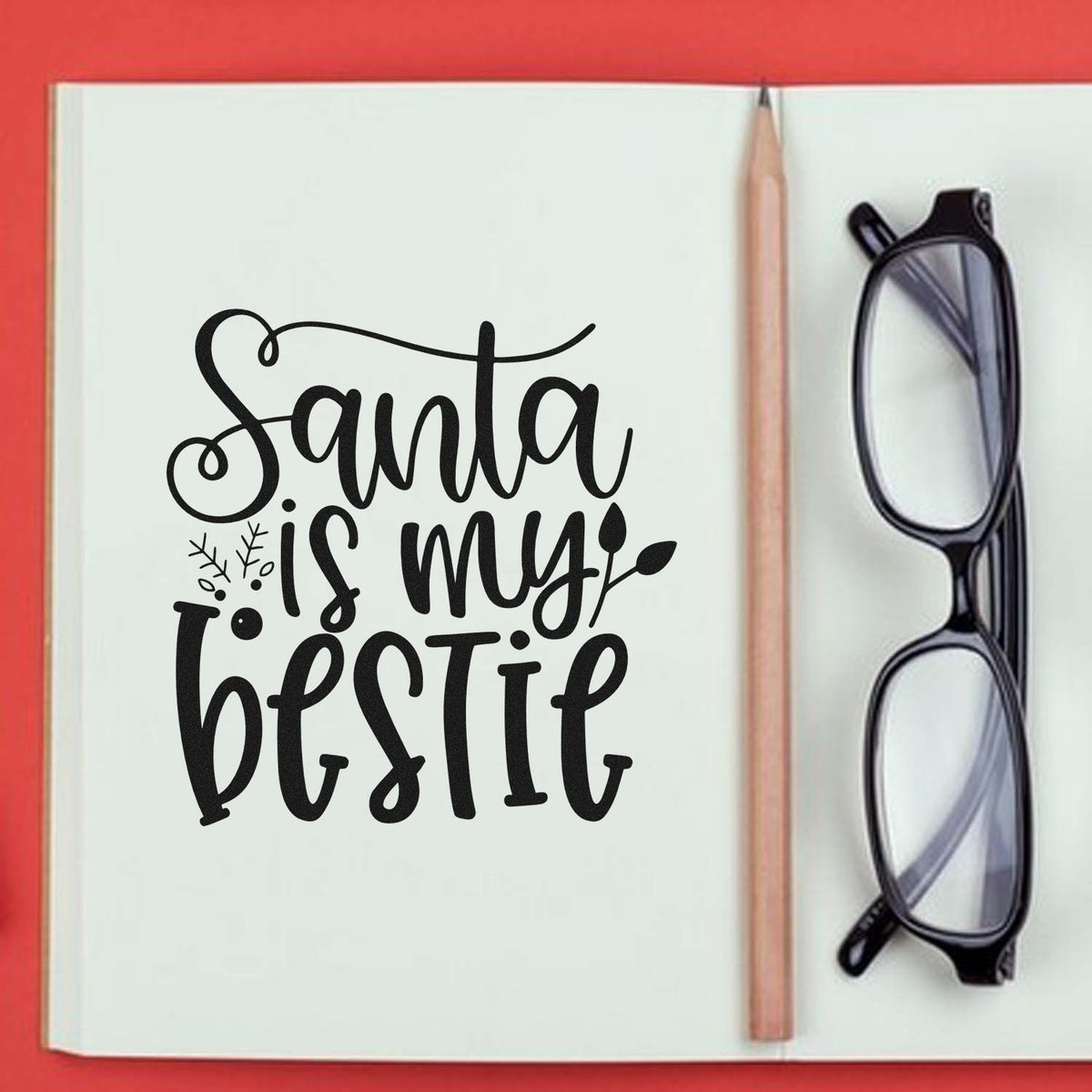Black Santa is my bestie stamp and seal on white notebook page, with pencil and eyeglasses on a red background.