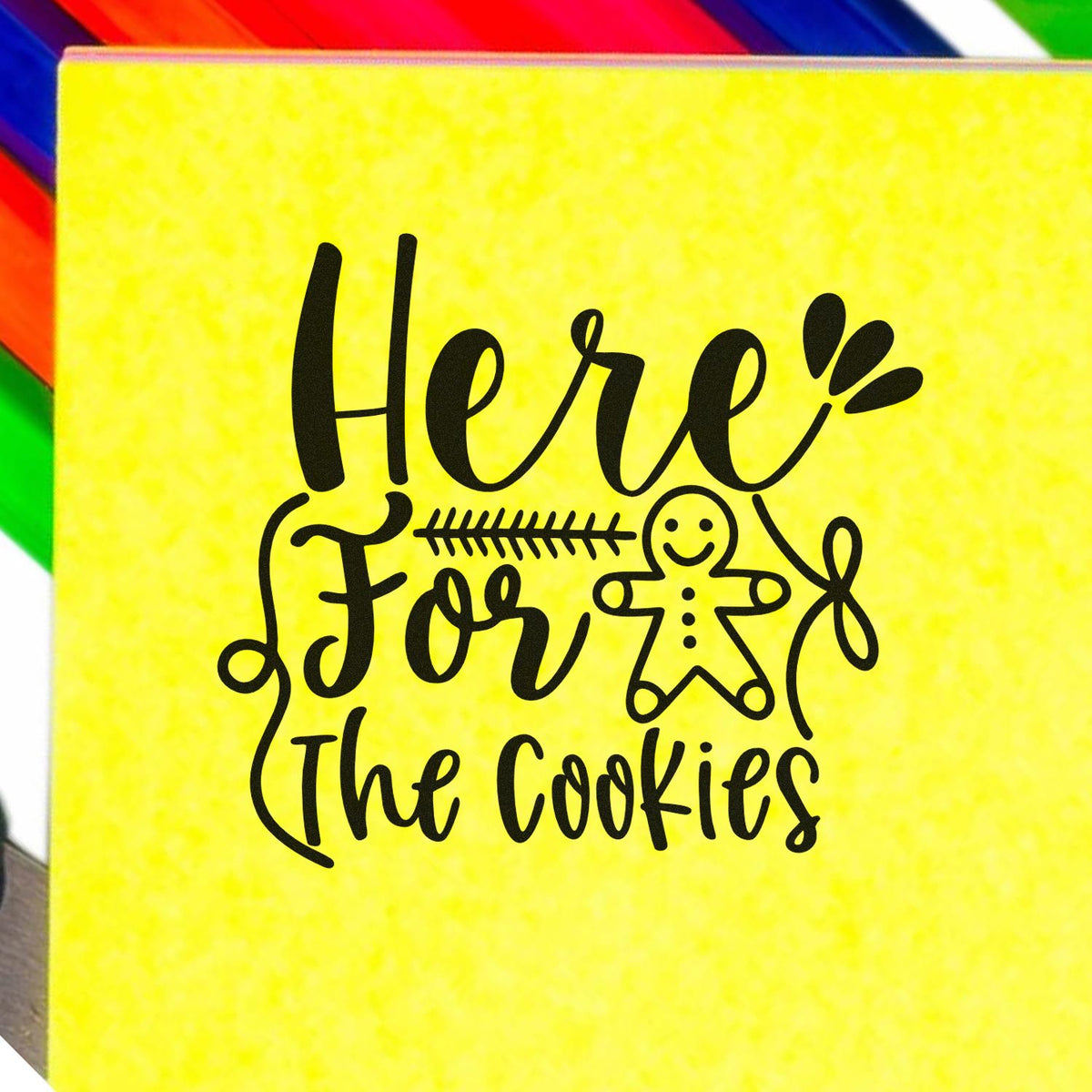 Yellow stamp and seal product with black Here For The Cookies lettering and gingerbread figure on a colorful striped background.