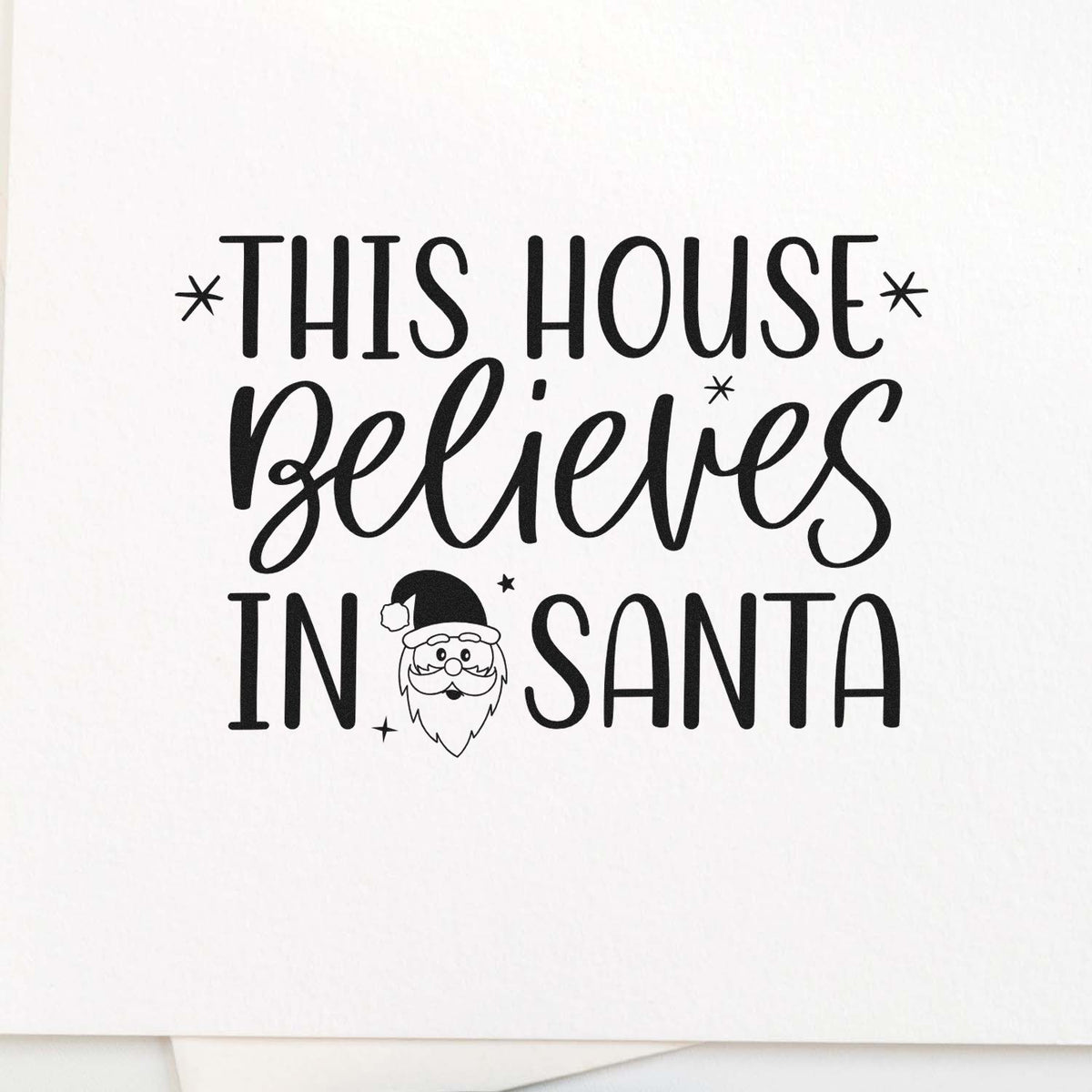 Black house stamp design reading This House Believes in Santa with Santa face icon and star accents on white background.