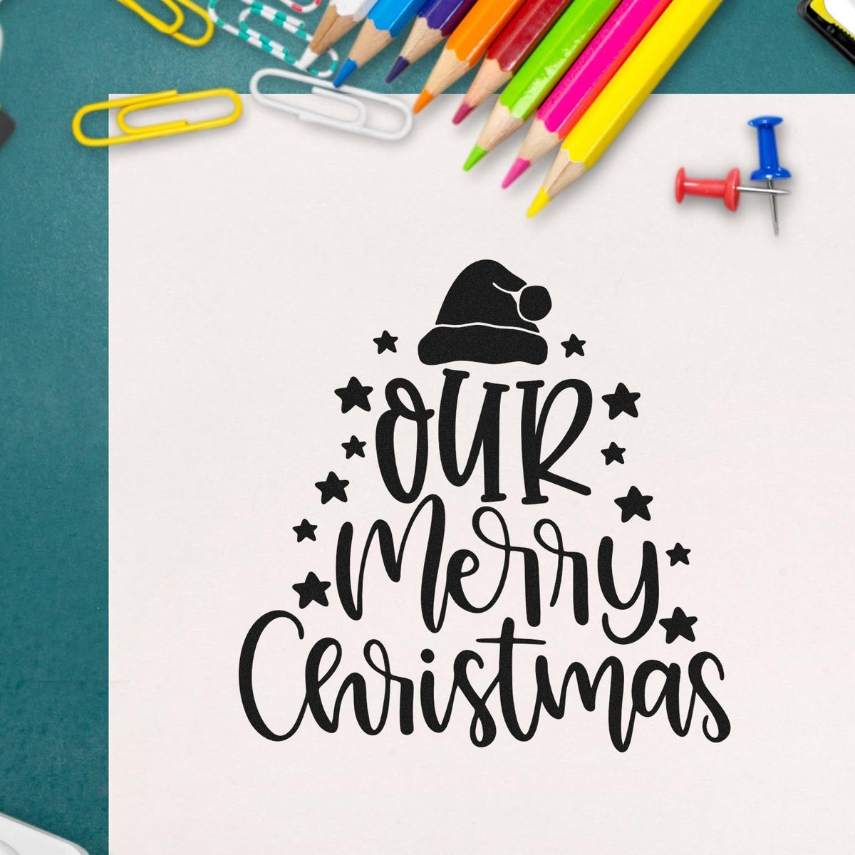 Black Our Merry Christmas stamp and seal design with Santa hat, stars, and colorful pencils on white paper.