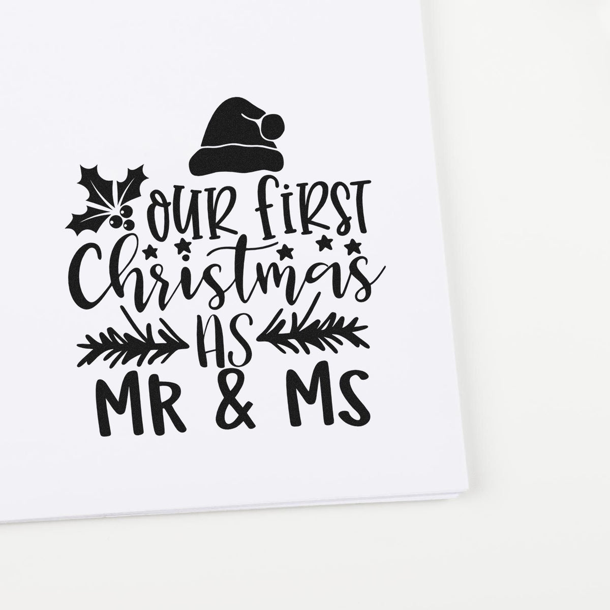 Black custom stamp design with Santa hat, holly and pine branches reading Our first Christmas as Mr & Ms on white.