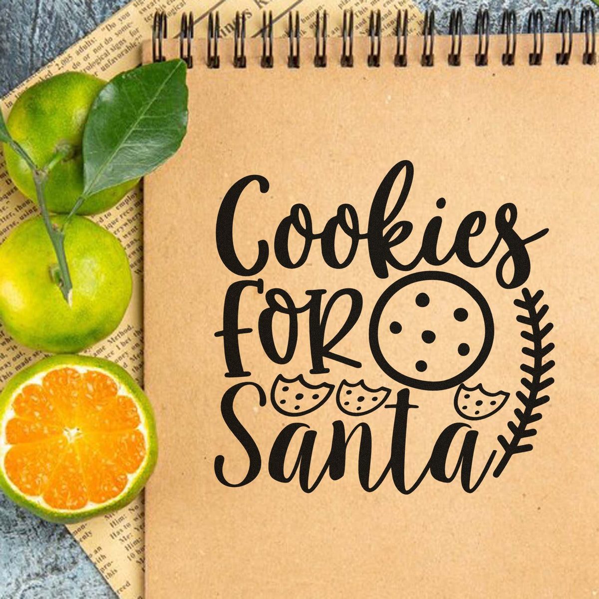 Black Cookies for Santa stamp and seal design on kraft notebook, with cookie icons, green leaves, and oranges.