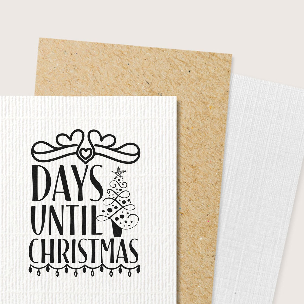 Black Days Until Christmas stamp design on white textured card, with hearts, snowflake and tree, layered over tan and white seal papers