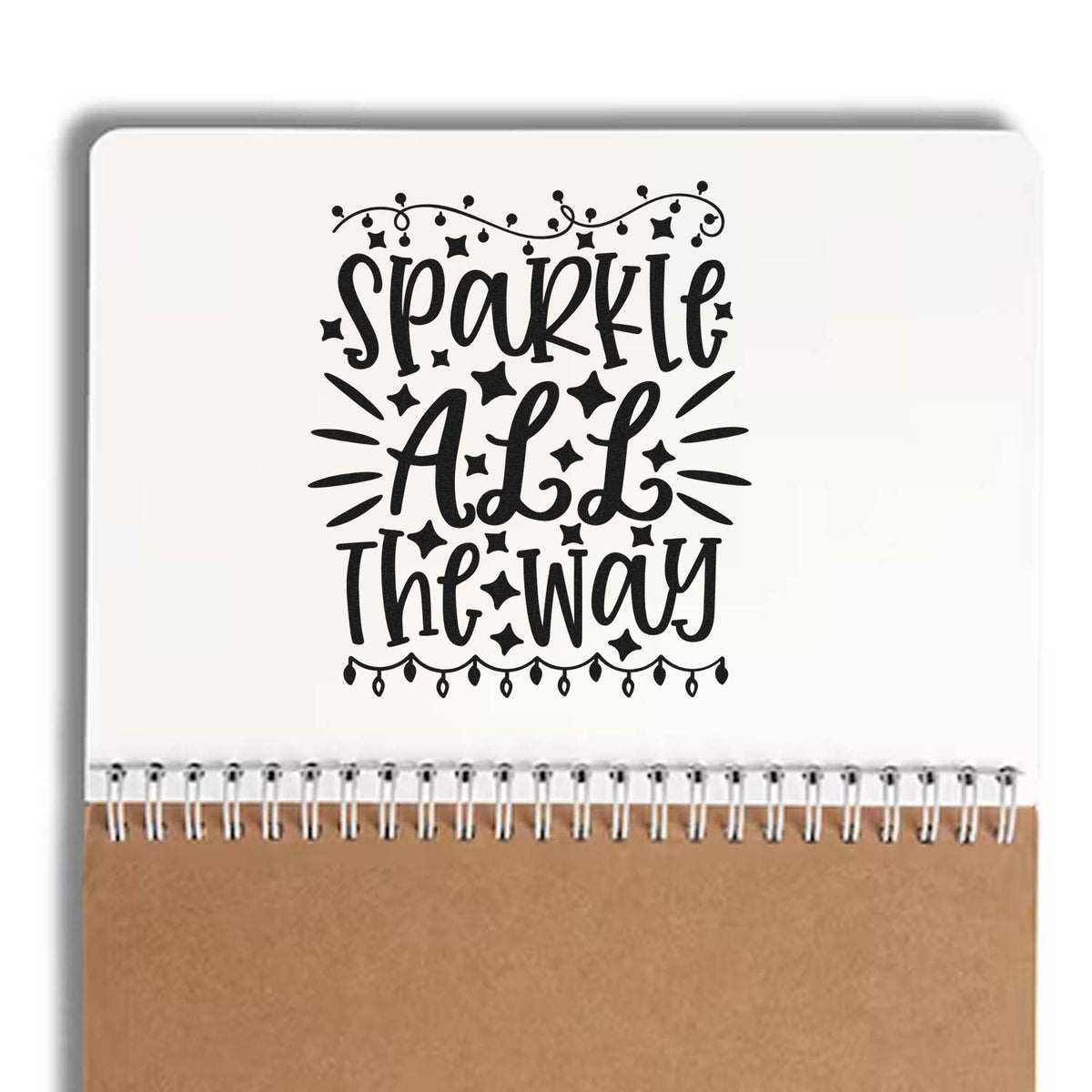 Black Sparkle All the Way decorative stamp on white notebook with brown kraft cover and spiral binding.