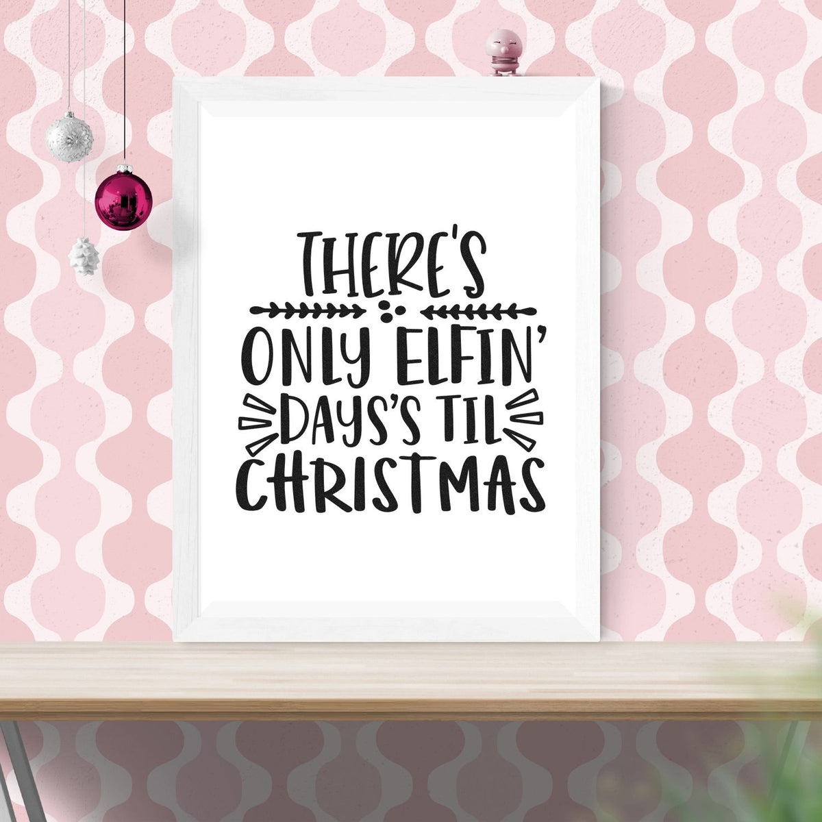 White framed Christmas stamp and seal print with black Theres only elfin days til Christmas text on pink patterned background