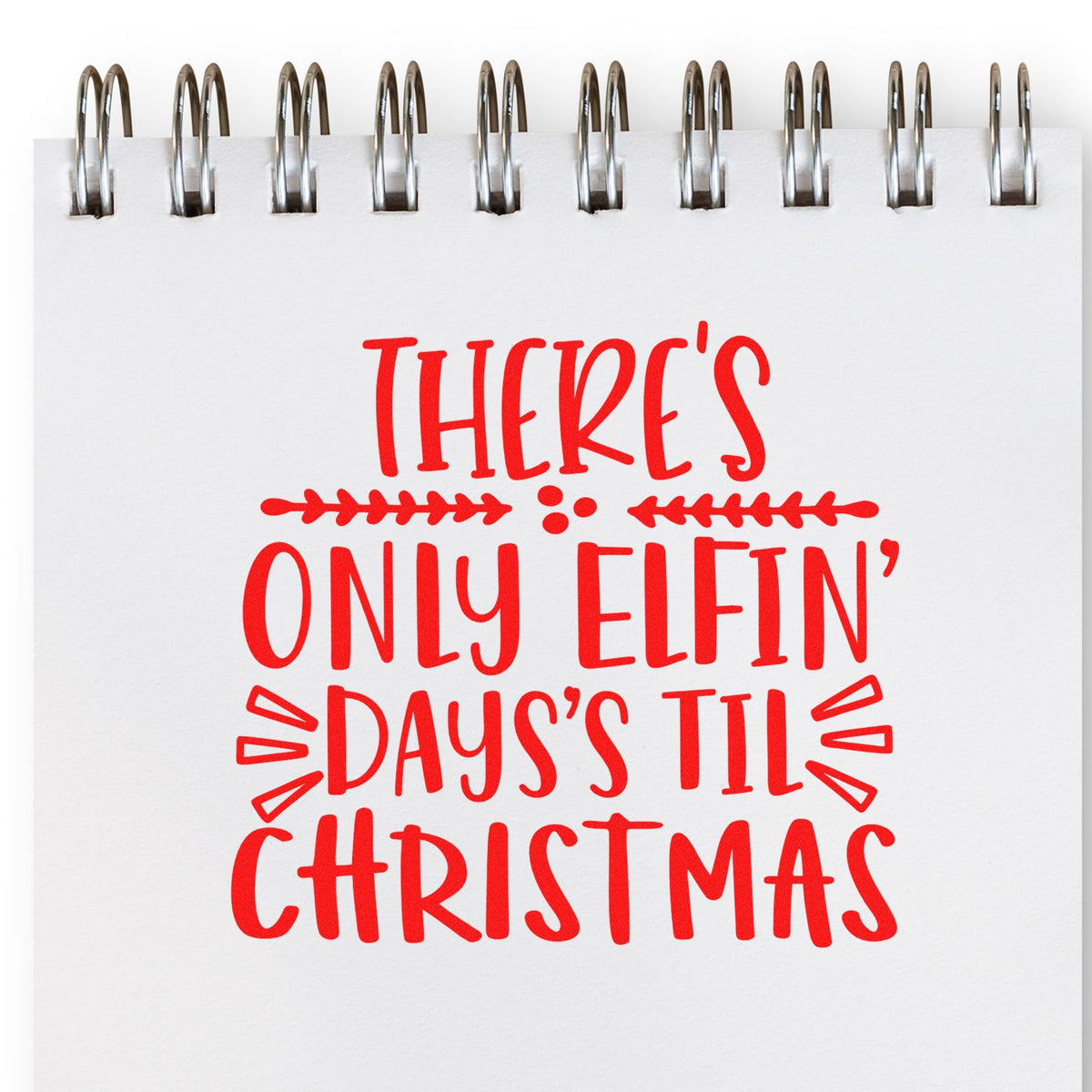 Red holiday stamp and seal on a white spiral-bound notebook reads Theres only elfin days til Christmas.