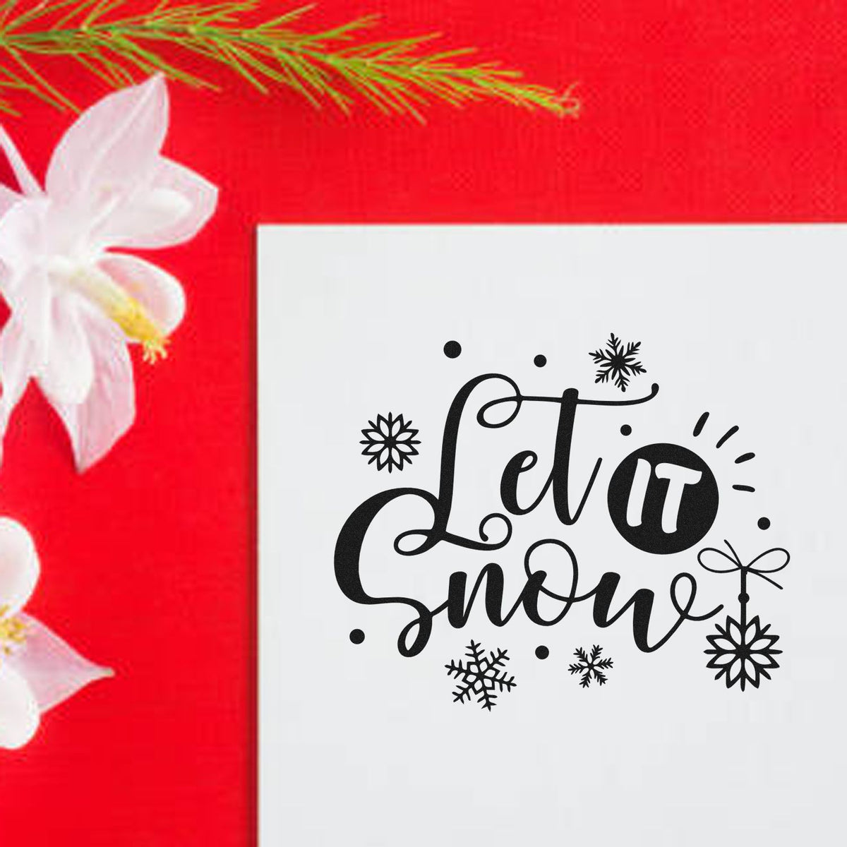 Winter stamp and seal design with black Let it snow text and snowflakes on a white card, set against a bright red floral background.