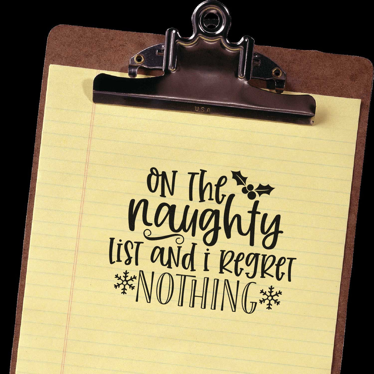 Holiday rubber stamp design on yellow lined paper reads On the naughty list and I regret nothing, with snowflakes on a clipboard.