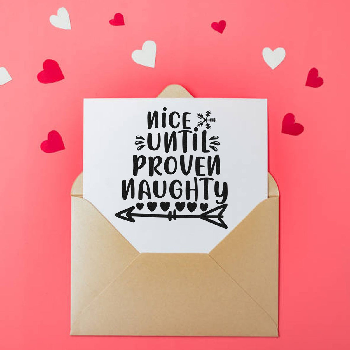 Holiday stamp and seal on beige envelope: black nice until proven naughty text, hearts, and arrow on pink background.