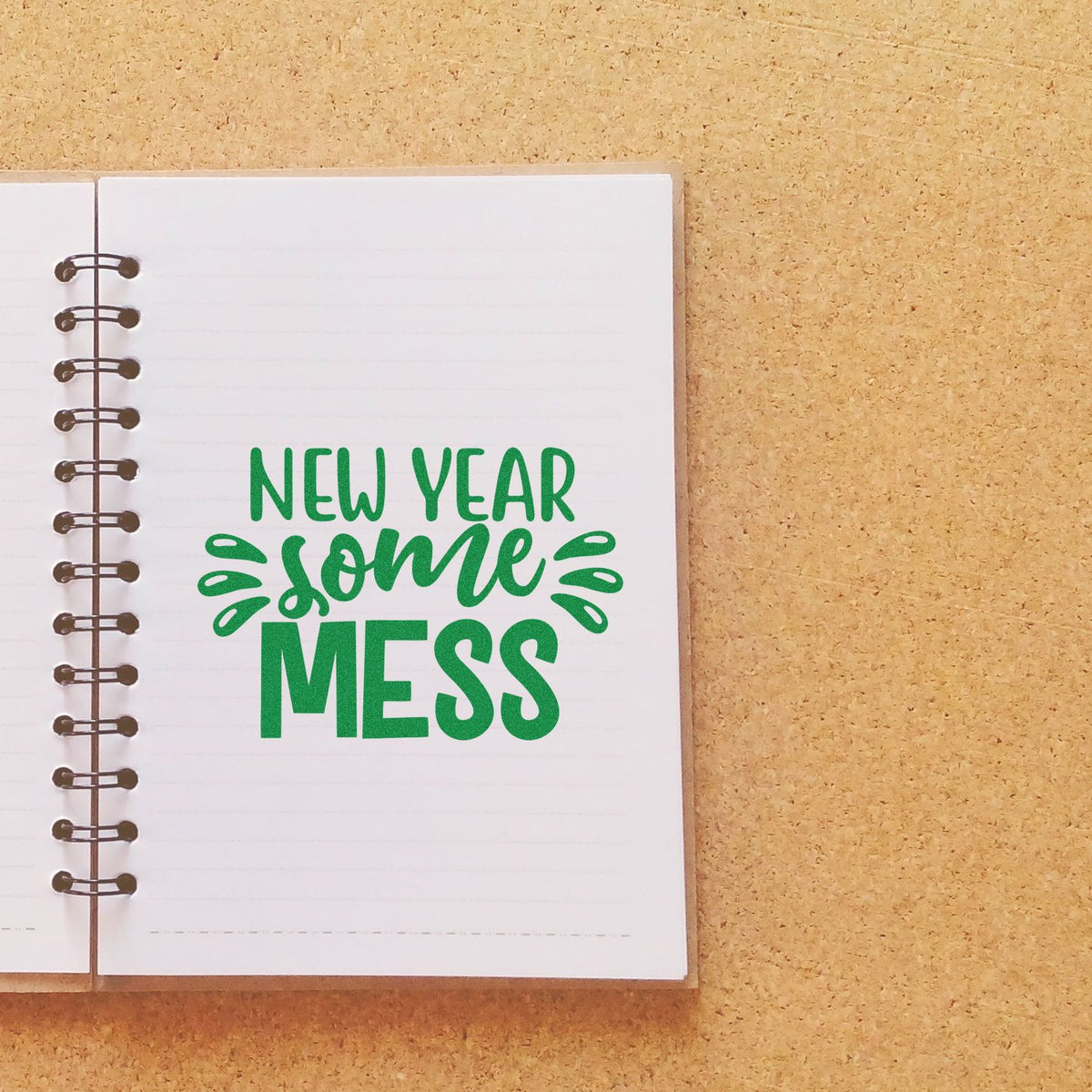 Green New Year Some Mess stamp and seal on a white spiral notebook over a tan cork background