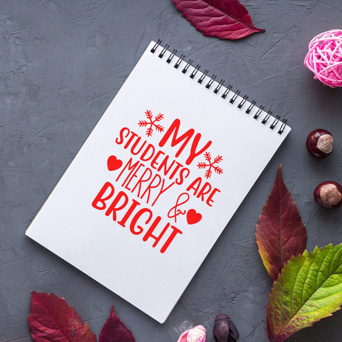 Red stamp design on white spiral notebook reading My Students Are Bright, with snowflakes and hearts on a gray background.