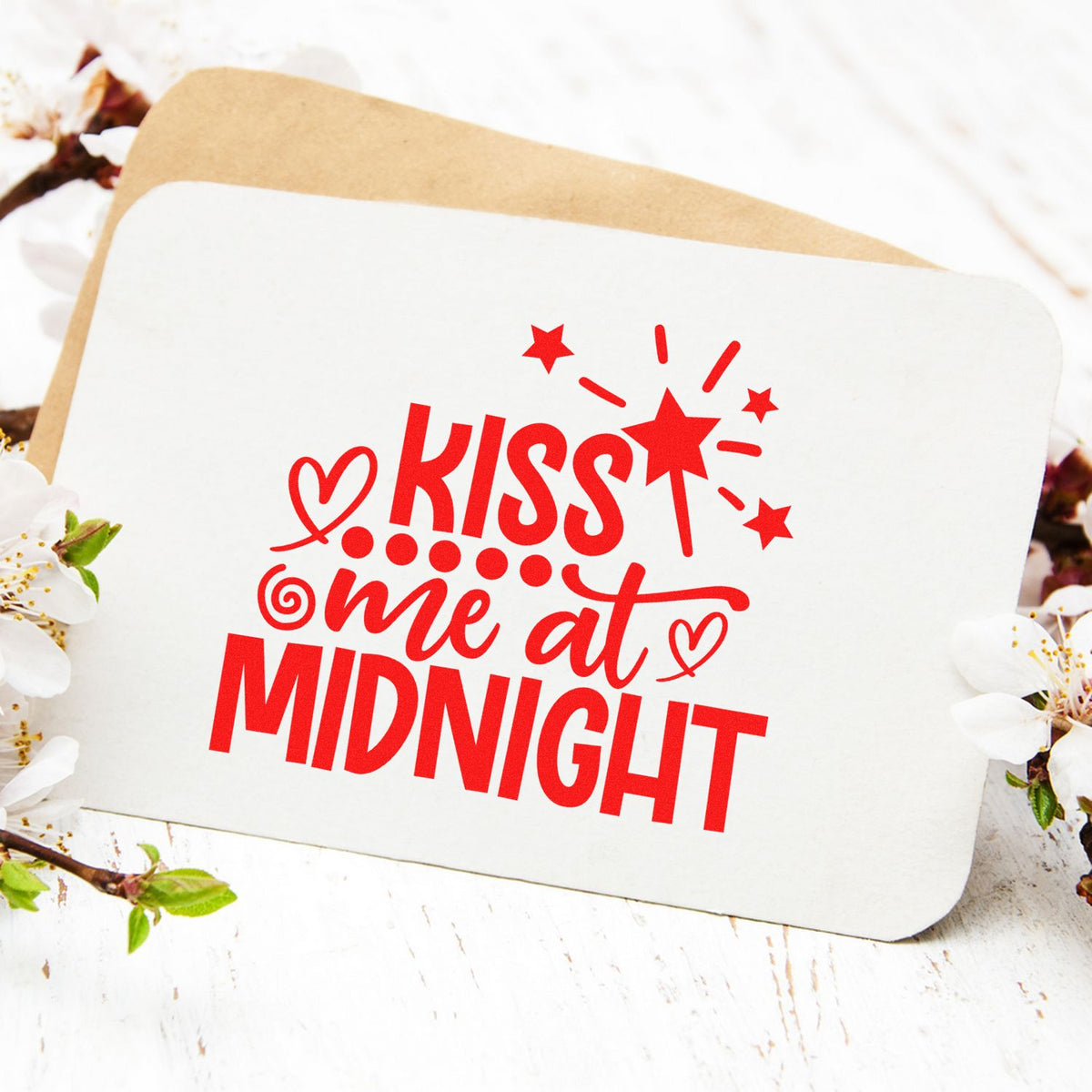 Red Kiss Me at Midnight stamp and seal on white card with stars and heart, layered over tan envelope and blossoms.
